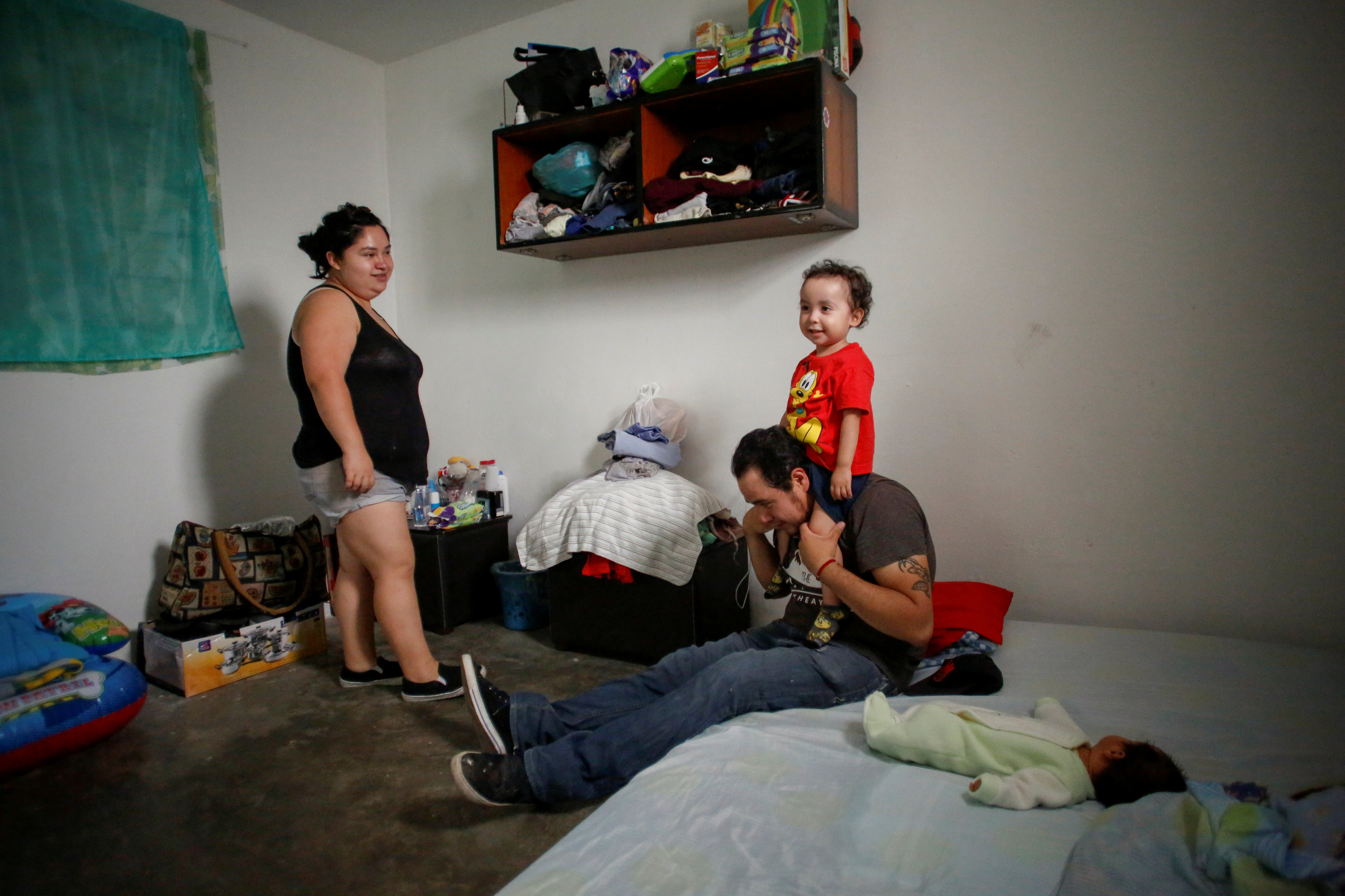 Karla López Rangel observa a su hijo Angel Flores López, de 3 años, sentado en los hombros de su esposo Miguel Flores Torres en su casa en Xochimilco, Ciudad de México , México, 17 de junio de 2020. Foto: REUTERS / Gustavo Graf.