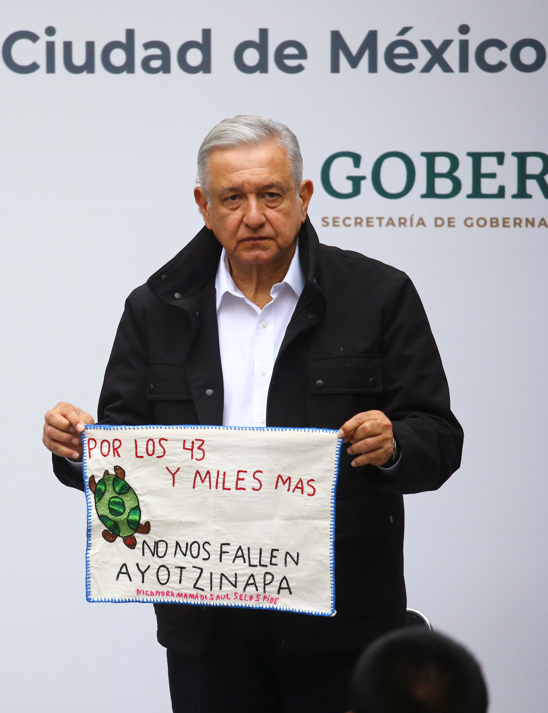 El presidente de México, Andrés Manuel López Obrador, sostiene una pieza de tela bordada por un familiar de uno de los 43 estudiantes desaparecidos de la Escuela Normal Rural de Ayotzinapa, mientras asisten a la entrega de un informe de investigación con motivo del sexto aniversario de su desaparición, en la Palacio en la Ciudad de México, México 26 de septiembre de 2020.