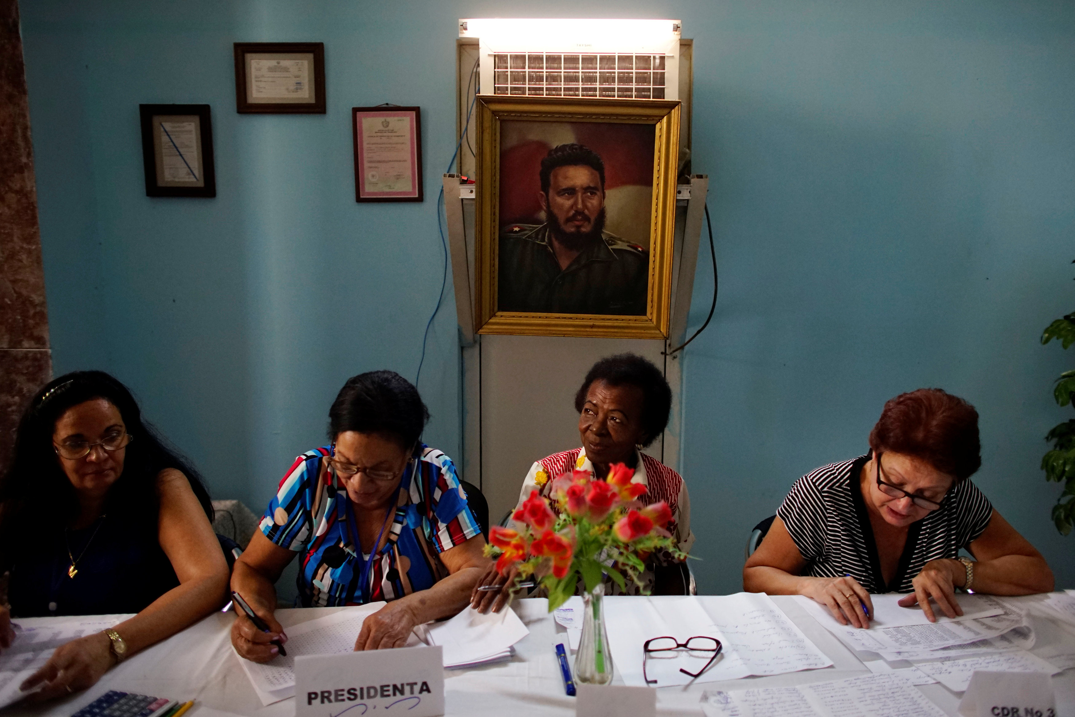 Funcionarios electorales comprueban los documentos de un votante en un colegio electoral, decorado con una imagen del fallecido  Fidel Castro, en La Habana, Cuba, 26 de noviembre de 2017 (REUTERS)