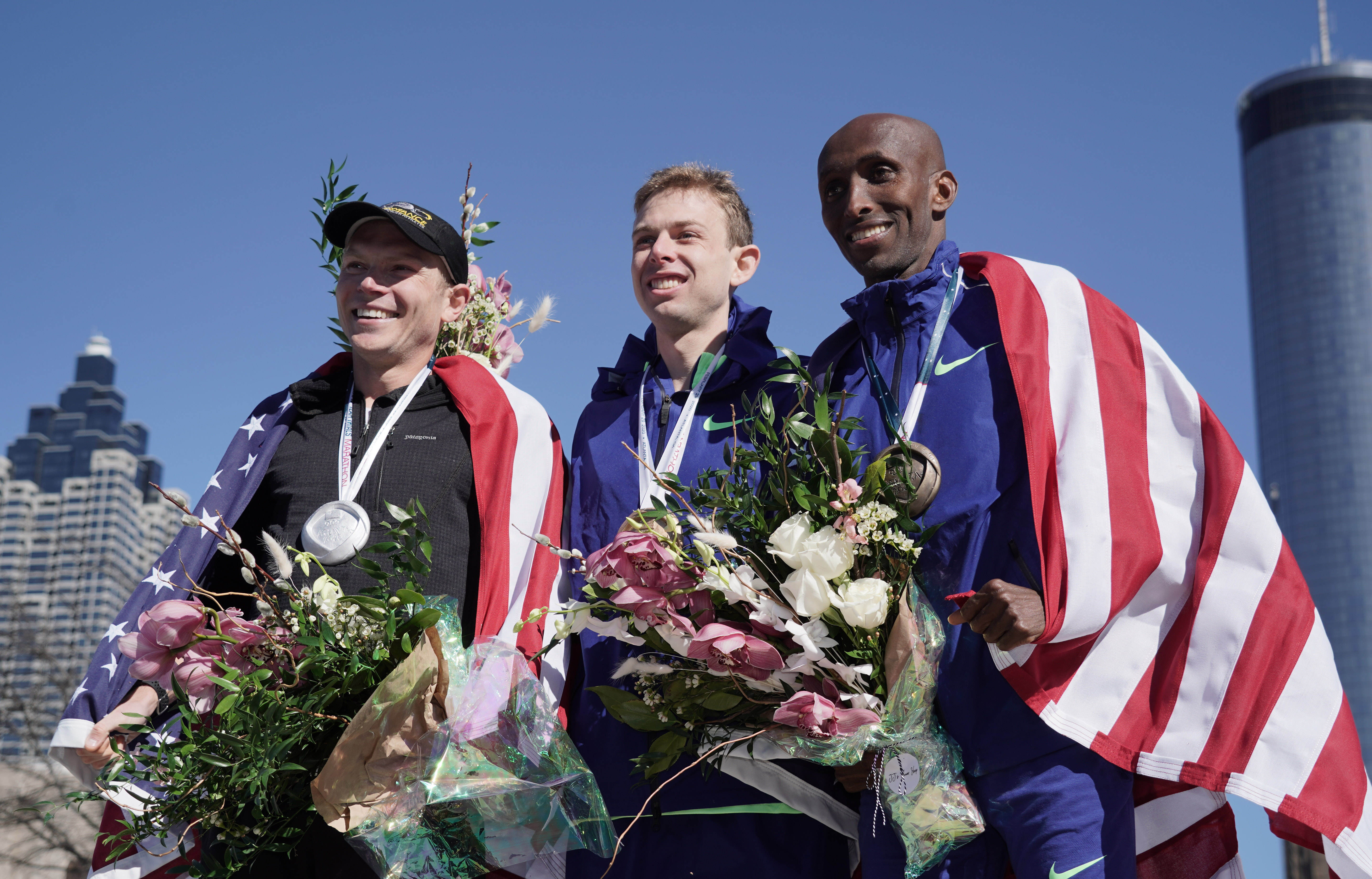 Feb 29, 2020; Atlanta, Georgia, USA; Men's winner Galen Rupp (center), runner-up Jacob Riley (left) and third-place finisher Abdi Abdirahman pose with Untied States flags afterthe US Olympic Team Trials marathon. Mandatory Credit: Kirby Lee-USA TODAY Sports