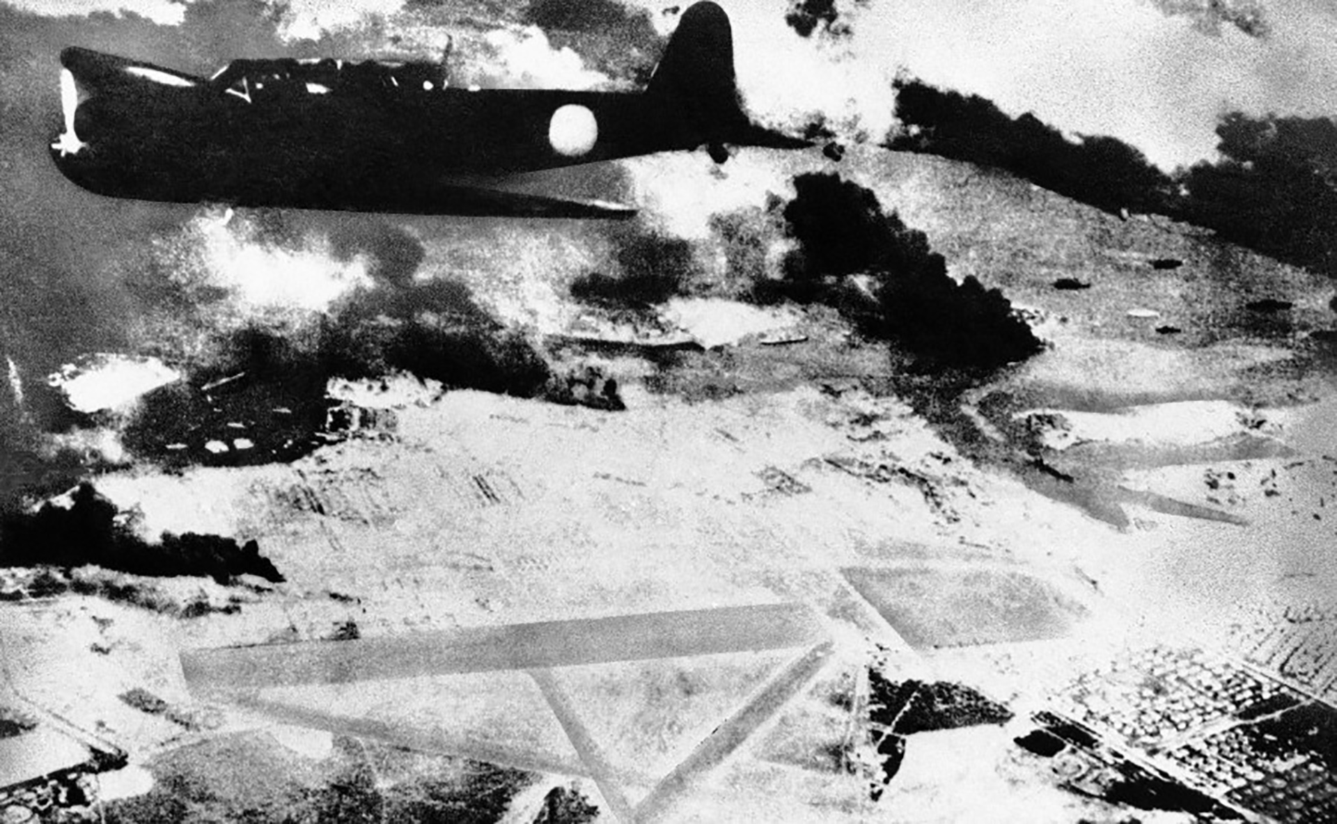 Un bombardero japonés sobre una pista de aviación en Pearl Harbor, Hawaii, durante el ataque por sorpresa del 7 de diciembre de 1941. El humo negro es de los buques norteamericanos alcanzados por las bombas (AP)