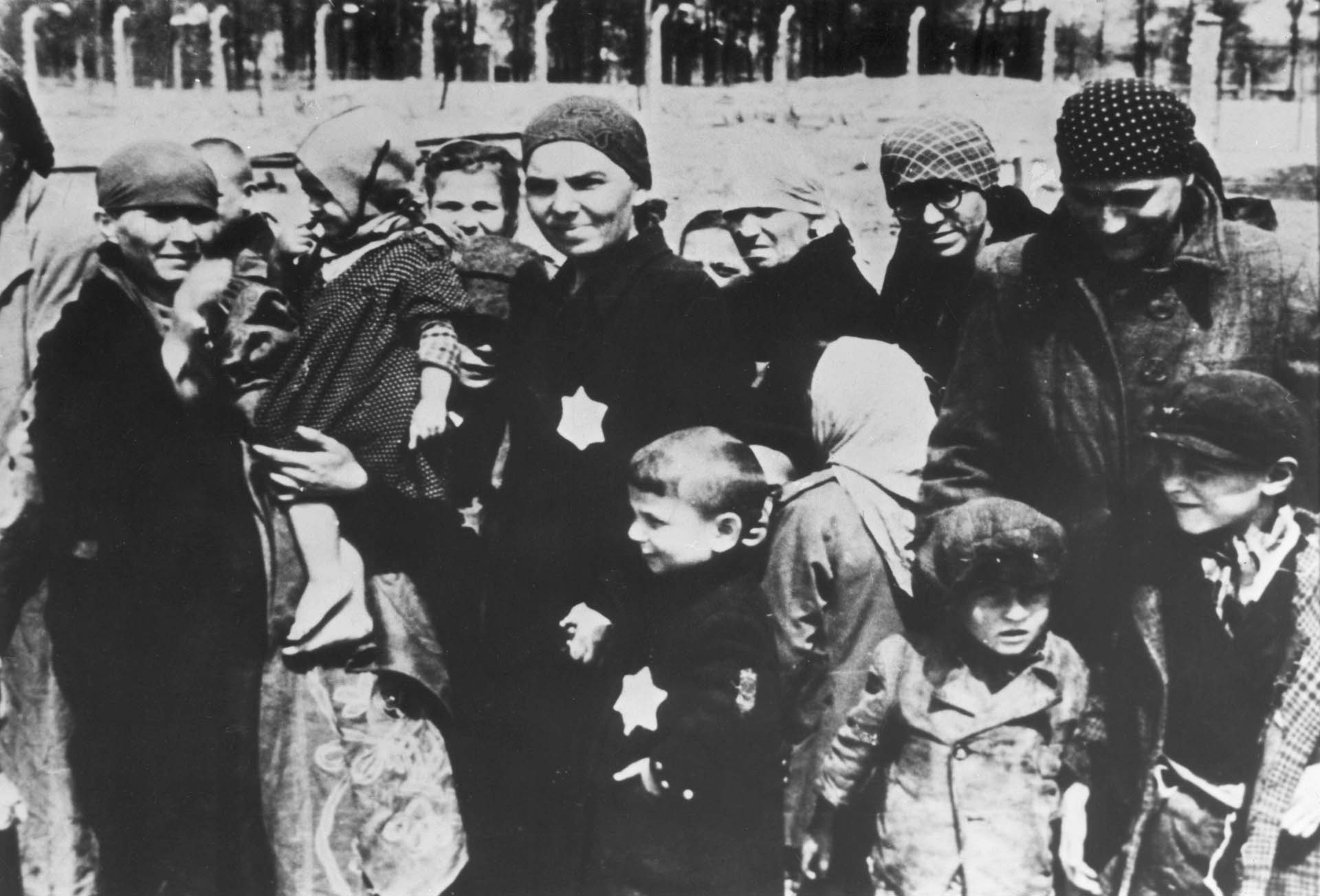 Mujeres y niños judíos, algunos llevando sobre sus ropas la estrella de David, en el anden del campo de concentración de Auschwitz.  Allí Mengele seleccionaba a quienes pasaban de inmediato a las cámaras de gas (Hulton Archive/Getty Images)