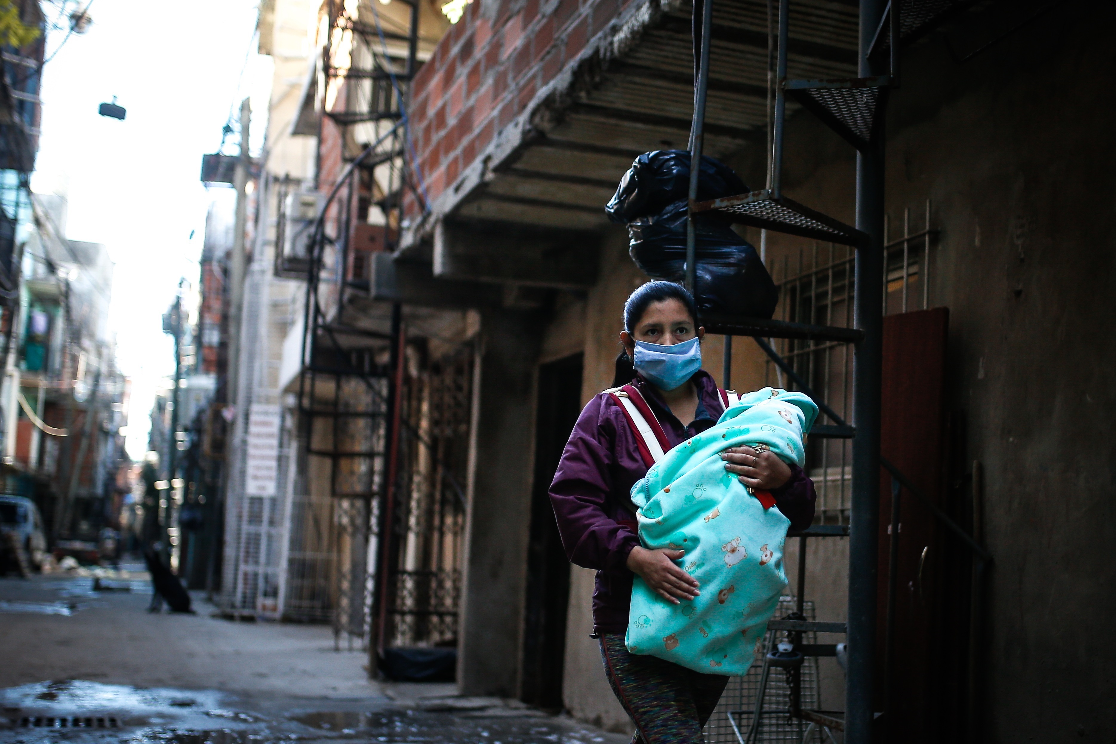 En la imagen, una mujer con tapabocas lleva a su beb&#233; por una calle de la Villa 31, en Buenos Aires (Argentina). EFE/Juan Ignacio Roncoroni/Archivo

