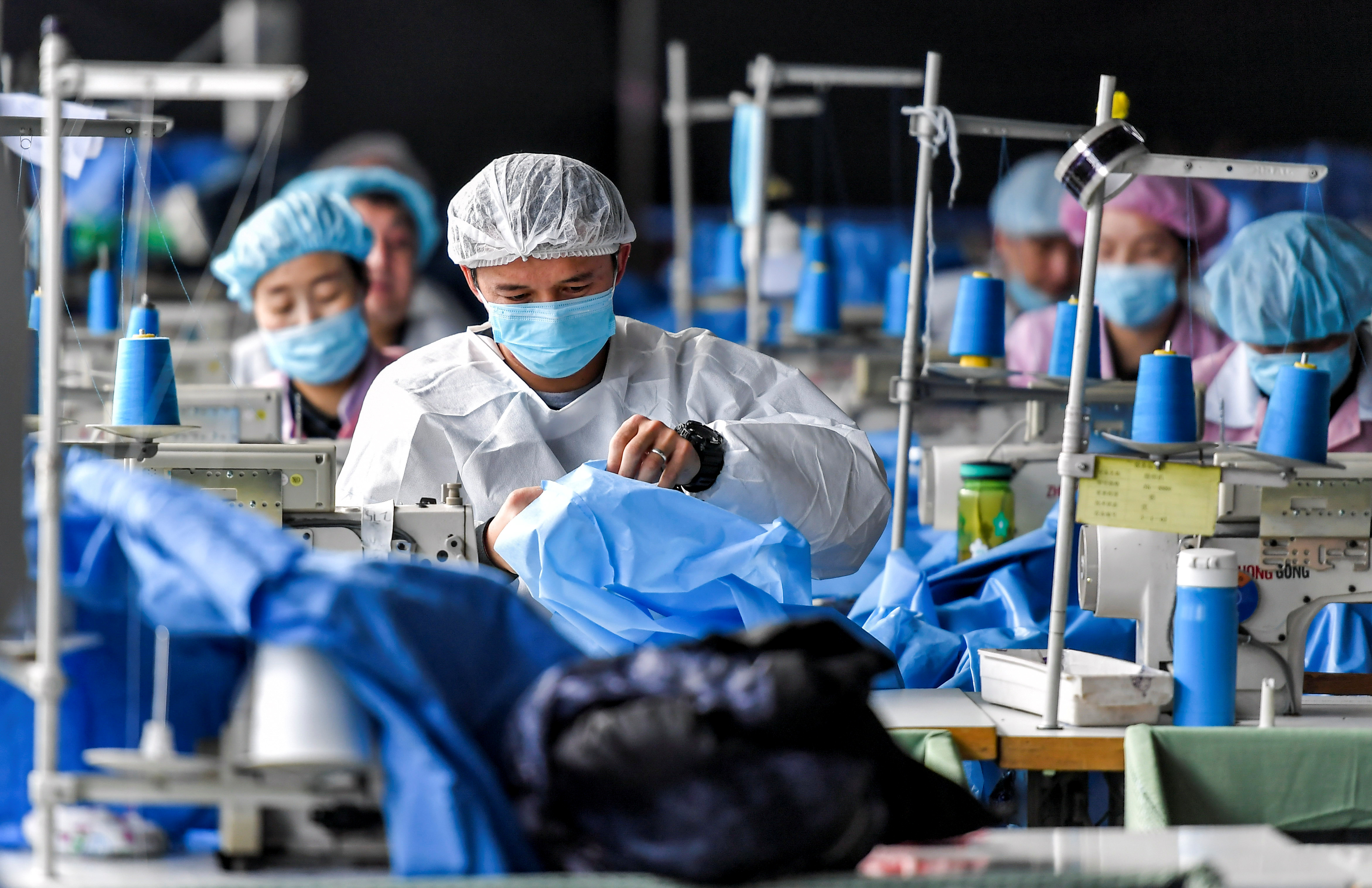 Trabajadores fabrican trajes de protección en una fábrica de equipos médicos en Urumqi, Región Autónoma Uigur de Xinjiang, China. Foto tomada el 27 de enero de 2020 (REUTERS)