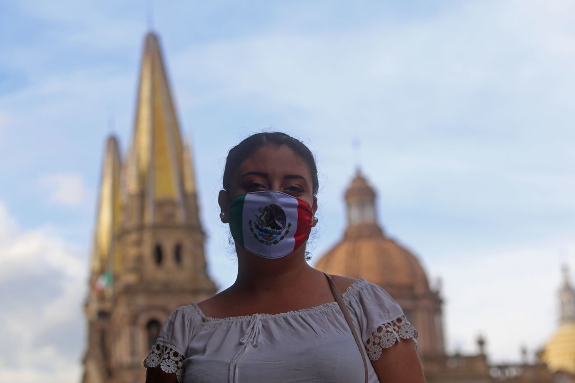 Una mujer posa para un retrato con cubrebocas de la bandera nacional de México, esto sobre avenida Alcalde y Morelos en donde al fondo se puede apreciar La Catedral Metropolitana.