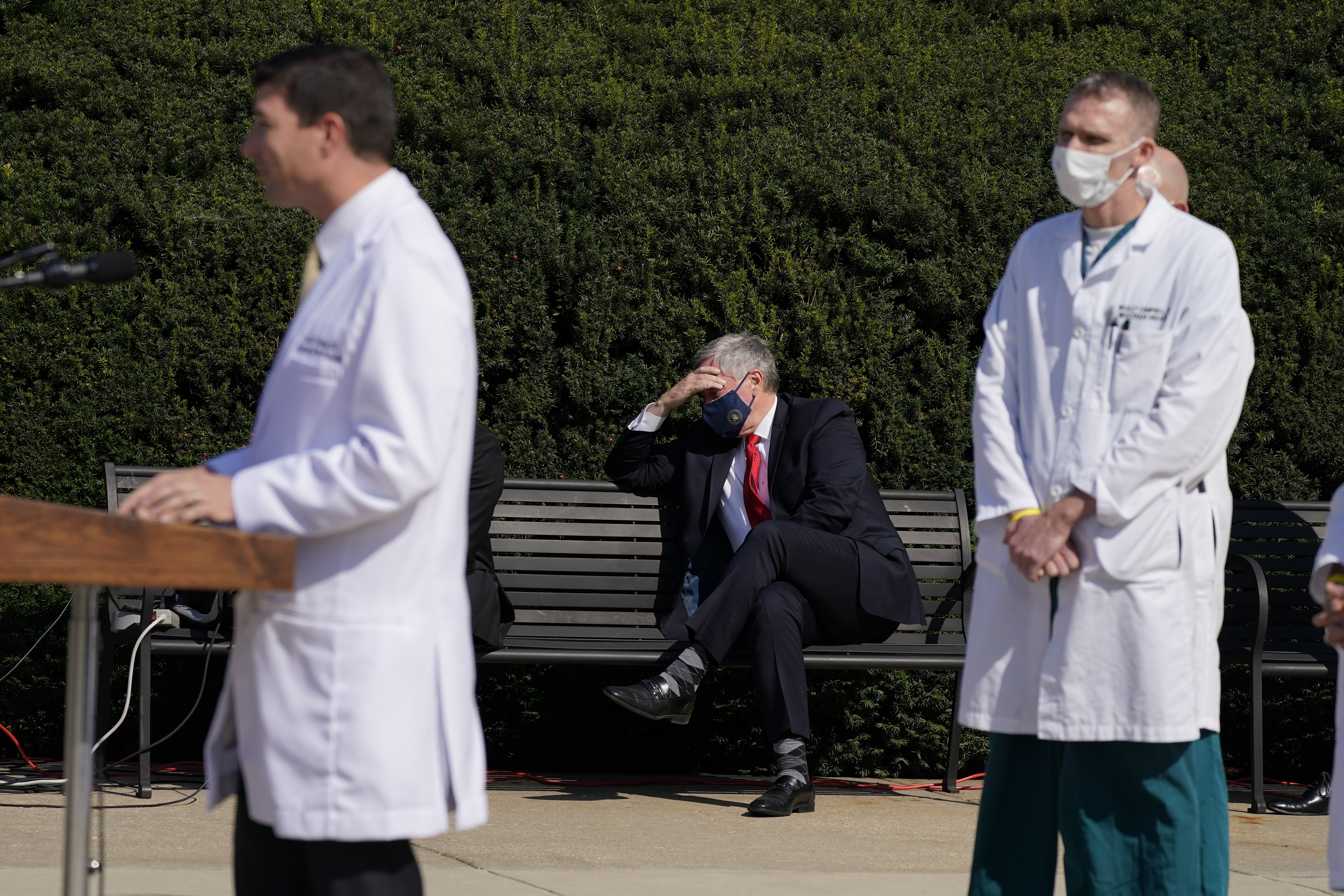 El jefe de despacho de la Casa Blanca Staff Mark Meadows (sentado, al centro) escucha mientras el médico del presidente Trump, Sean Conley, da una conferencia de prensa (AP)
