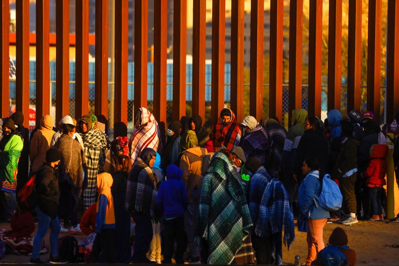 Migrantes hacen fila cerca de la valla fronteriza, después de cruzar el río Bravo, para entregarse a agentes de la Patrulla Fronteriza de Estados Unidos y solicitar asilo, en El Paso, Texas (REUTERS/José Luis González)