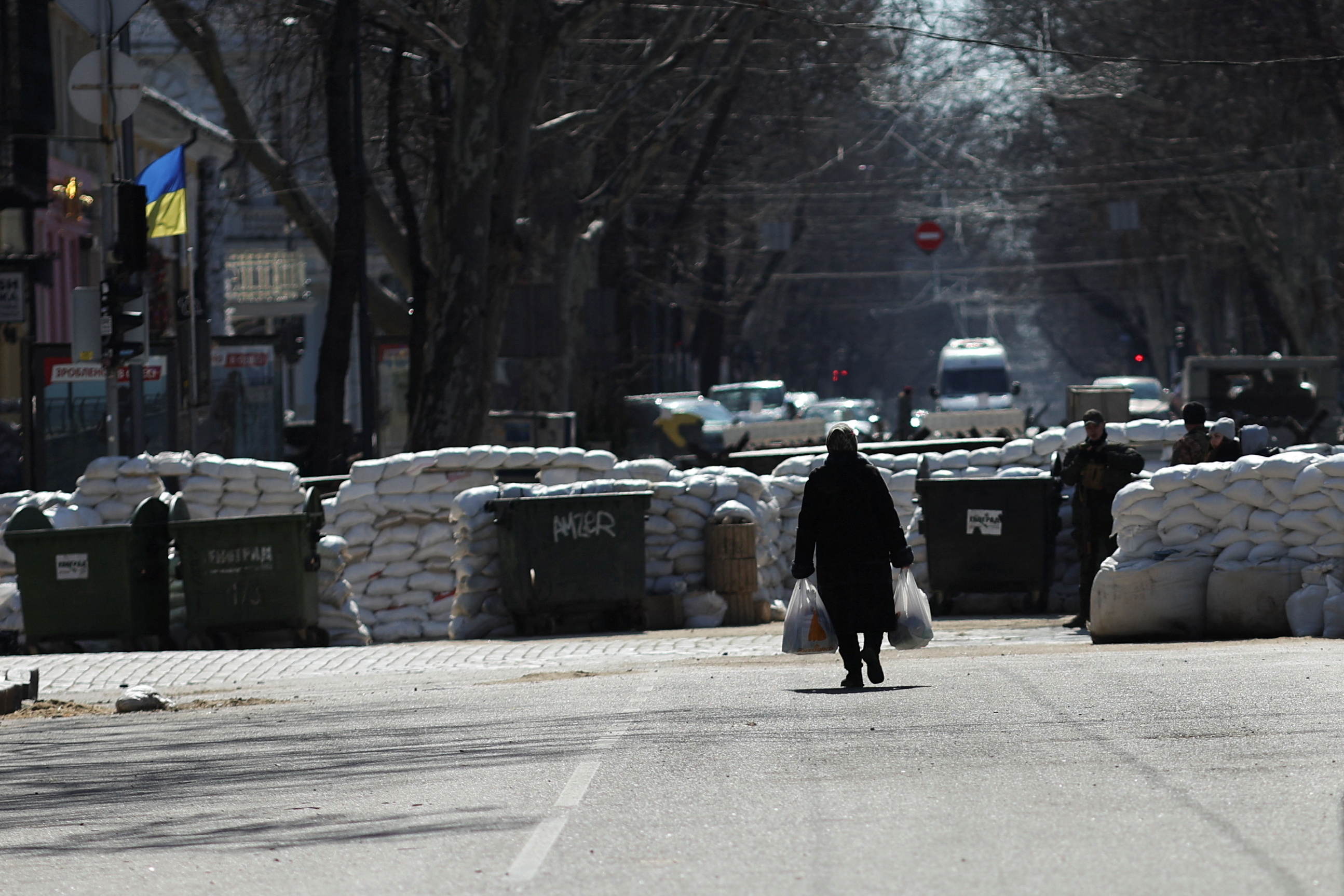 An elderly woman walks near barriers placed on a street, as Russia's invasion of Ukraine continues, in downtown Odessa, Ukraine, March 17, 2022. REUTERS/Nacho Doce