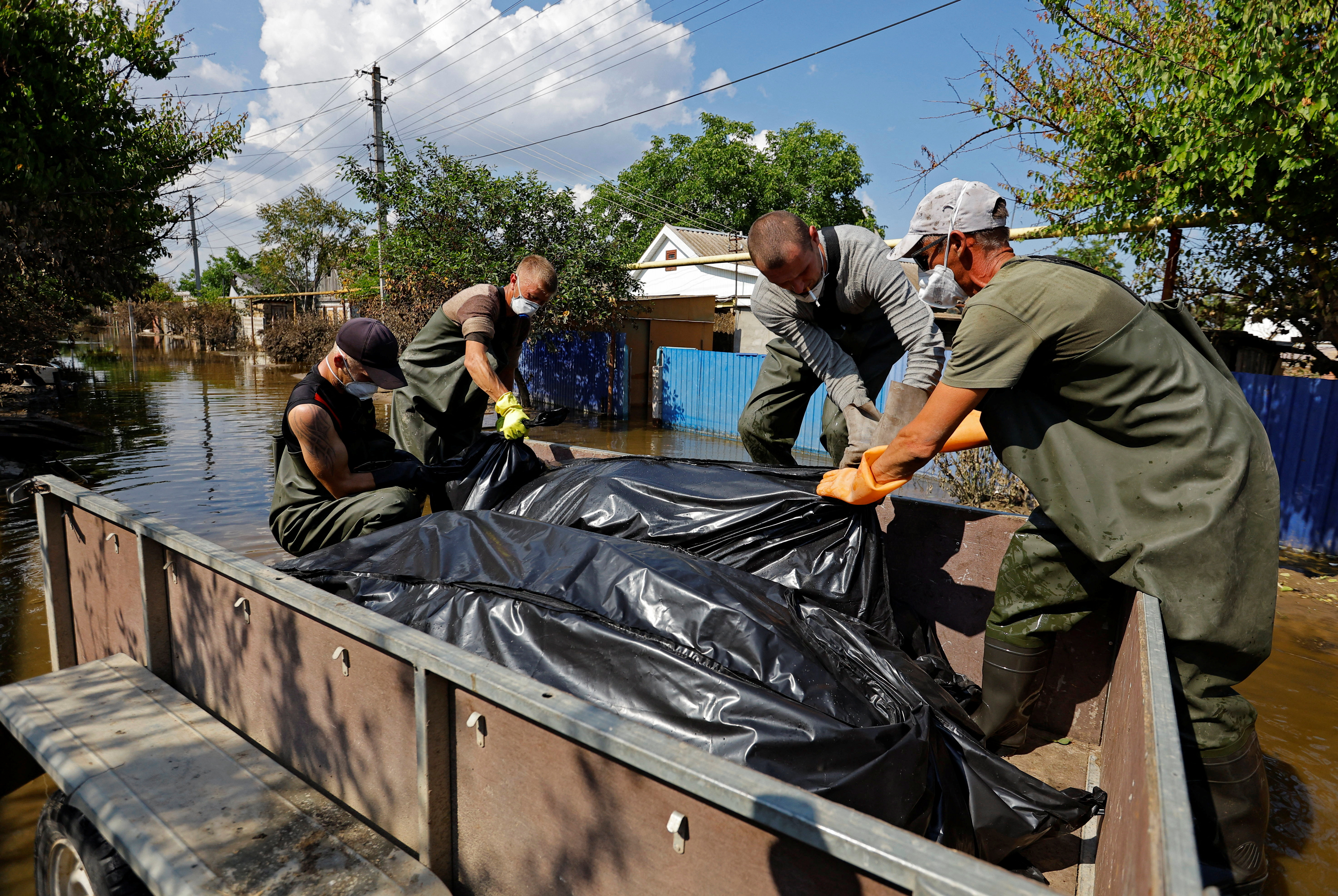 Voluntarios y trabajadores municipales colocan bolsas con cuerpos recuperados de casas inundadas tras el colapso de la presa de Nova Kakhovka. REUTERS/Alexander Ermochenko