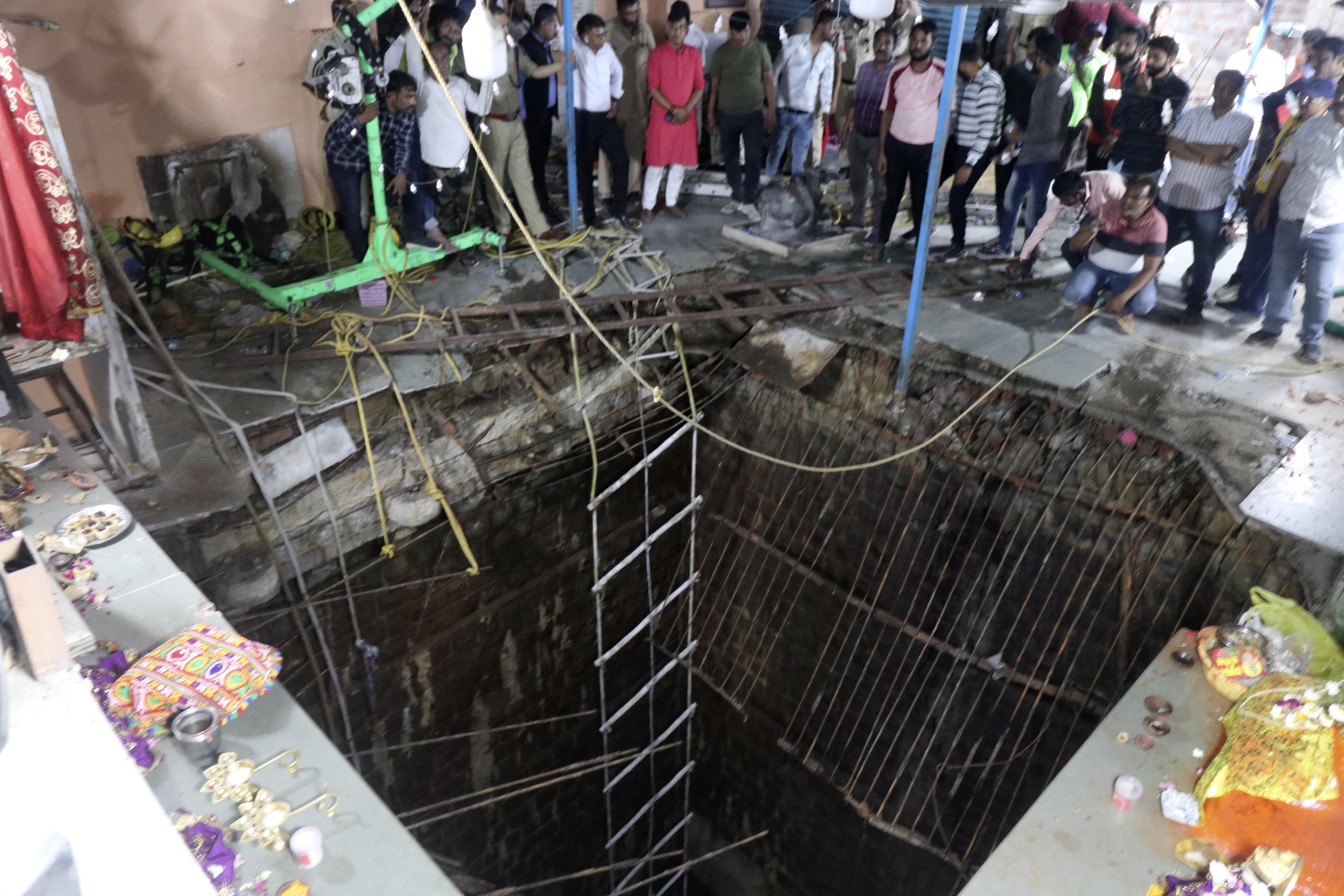 Gente rodea una estructura construida sobre el pozo de un templo antiguo que se derrumbó el jueves cuando una gran cantidad de fieles acudieron al festival hindú de Ram Navami en Indore, India, jueves 30 de marzo de 2023. Unas 35 personas cayeron al pozo al derrumbarse la estructura y quedaron cubiertas por los escombros, dijo el jefe de policía Makrand Deoskar. Al menos ocho murieron. (AP Foto)