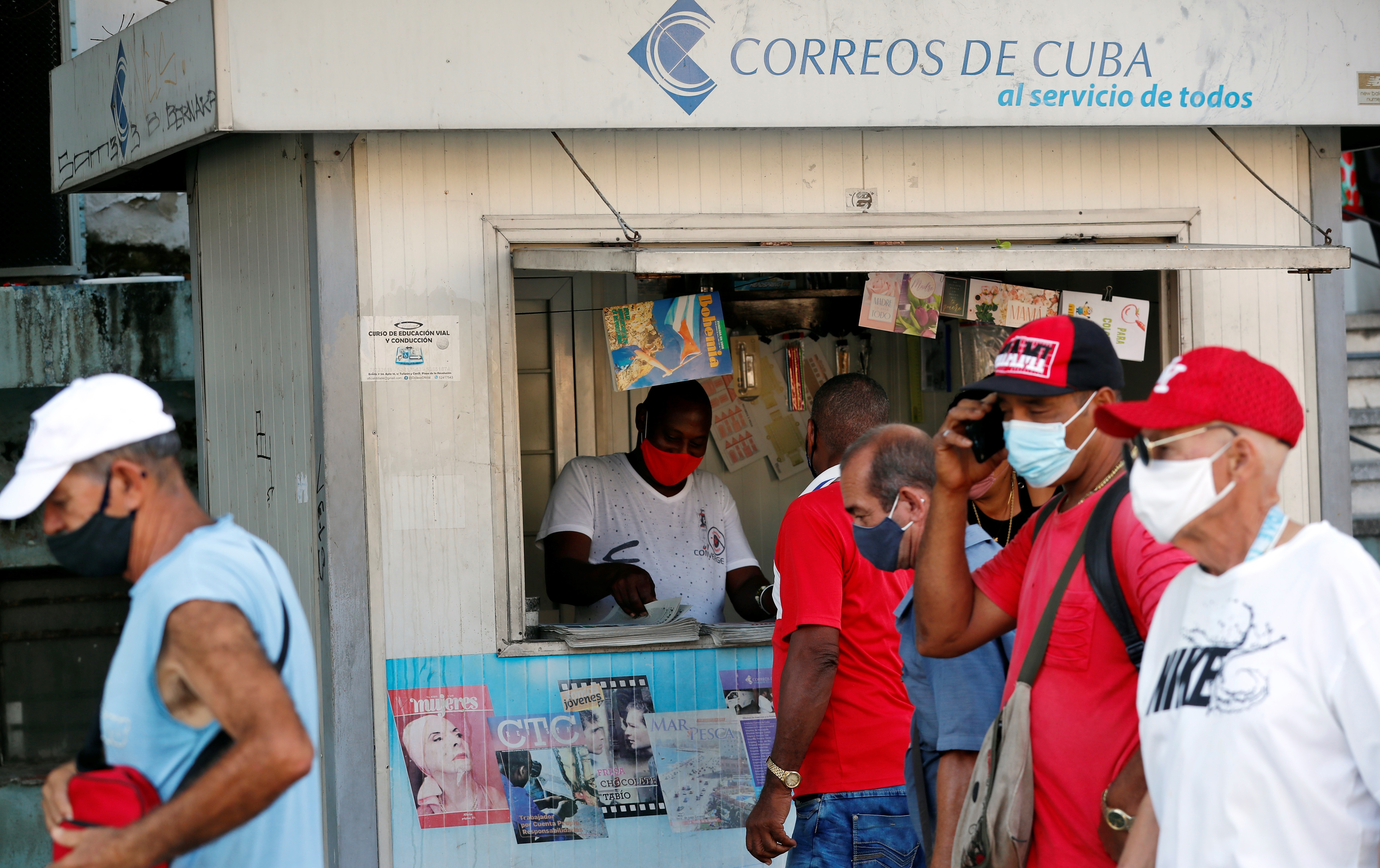 Varias personas con tapabocas pasan frente a un puesto de venta de revistas y periódicos, en La Habana (Cuba). EFE/Ernesto Mastrascusa/Archivo
