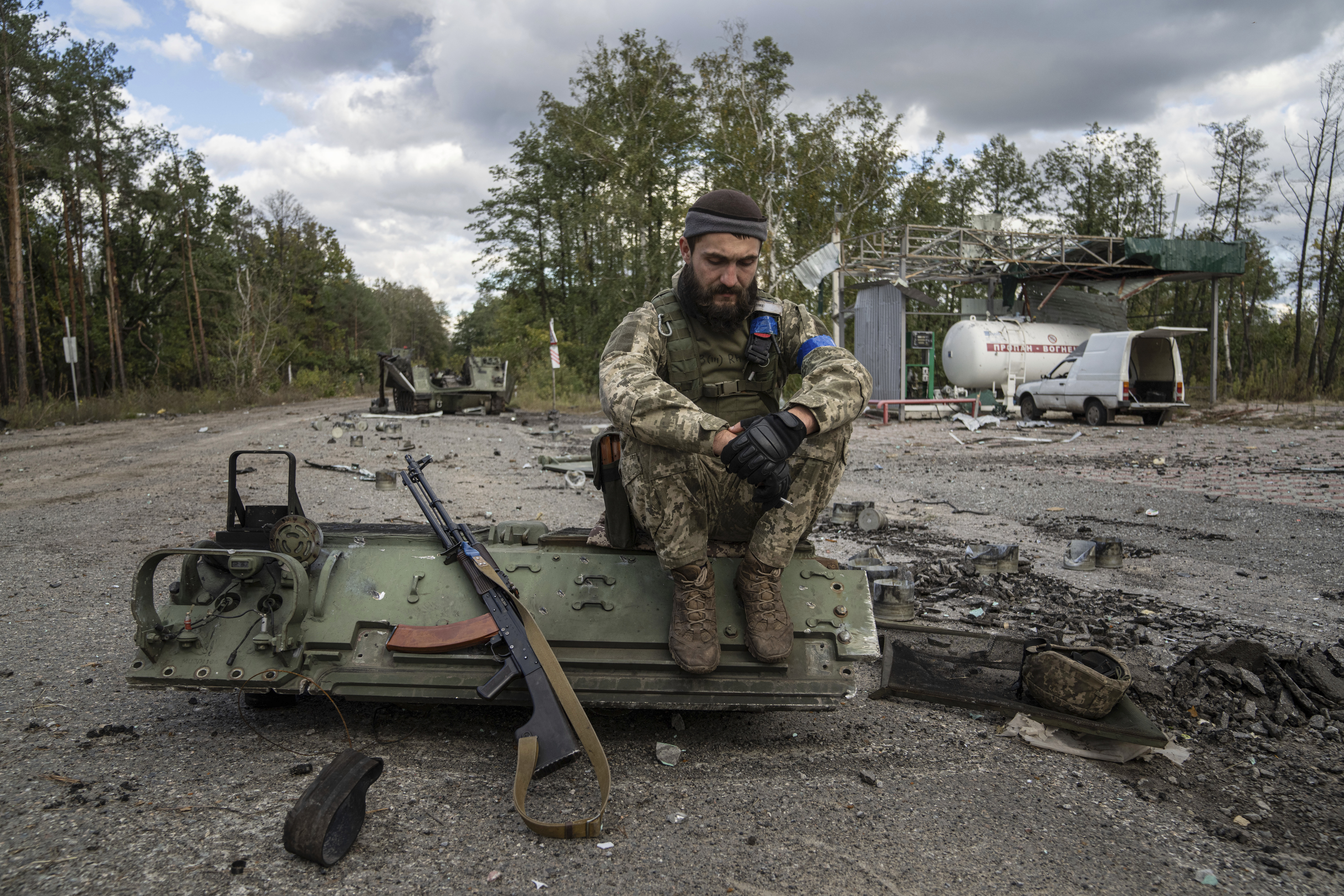 Un militar ucraniano fuma un cigarrillo después de encontrar e identificar el cadáver de un camarada (AP/Evgeniy Maloletka)