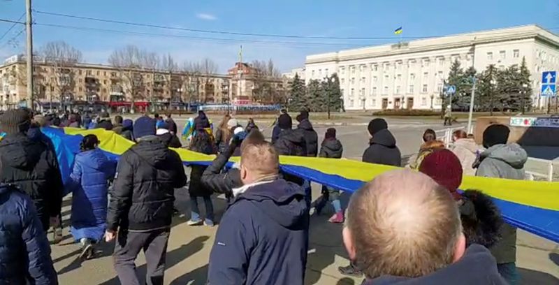 FOTO DE ARCHIVO. Imágenes transmitidas en directo muestran a personas portando una pancarta con los colores de la bandera ucraniana mientras protestan en medio de la invasión rusa de Ucrania, en Jersón, Ucrania. 13 de marzo de 2022, en esta imagen fija de un vídeo de las redes sociales obtenido por REUTERS