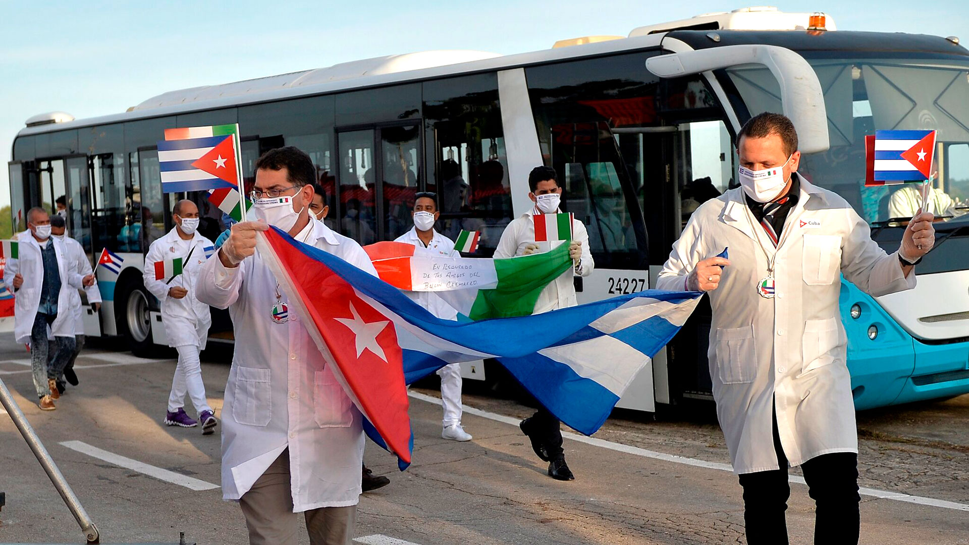 Médicos cubanos ondeaban banderas de Cuba e Italia el año pasado, cuando regresaron a casa después de una misión para ayudar a combatir el coronavirus en Italia. (Foto de consorcio de Yamil Lage)