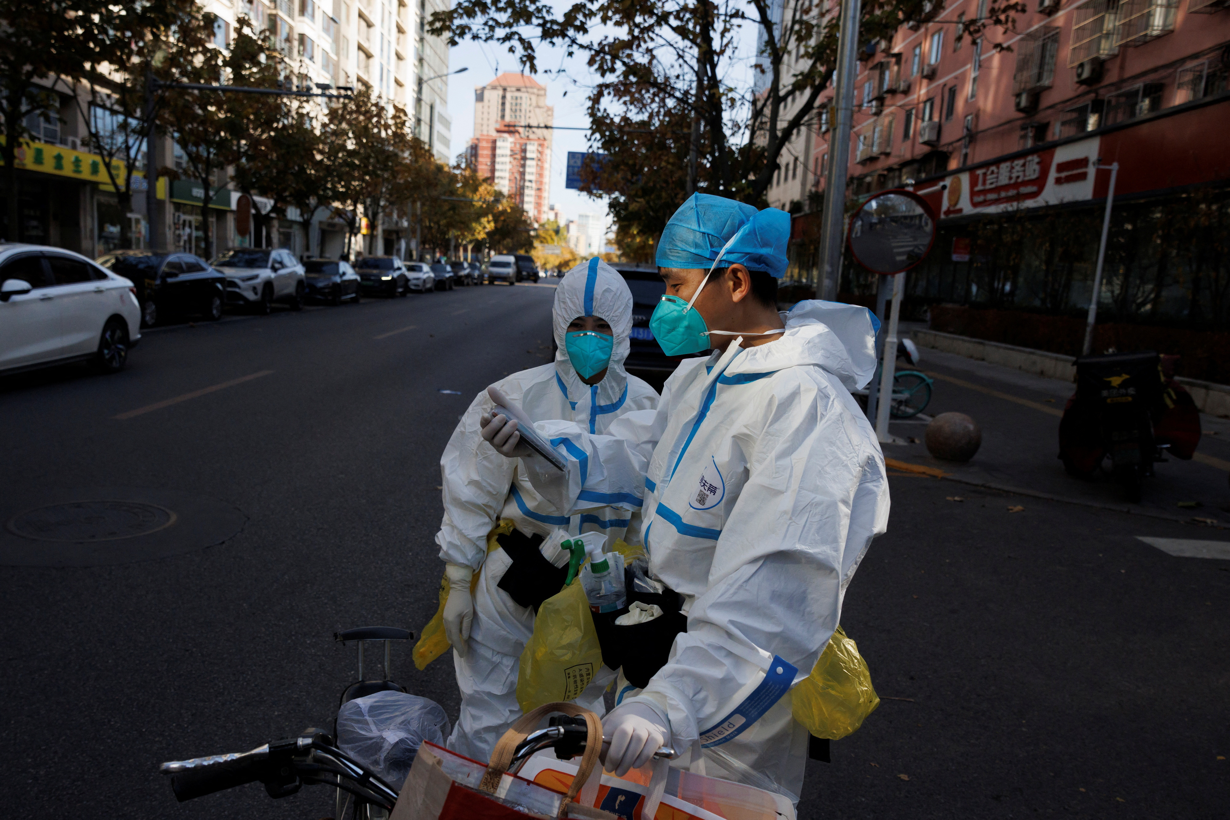 Pandemic prevention workers in protective suits stand on a street as outbreaks of the coronavirus disease (COVID-19) continue in Beijing.  REUTERS/Thomas Peter