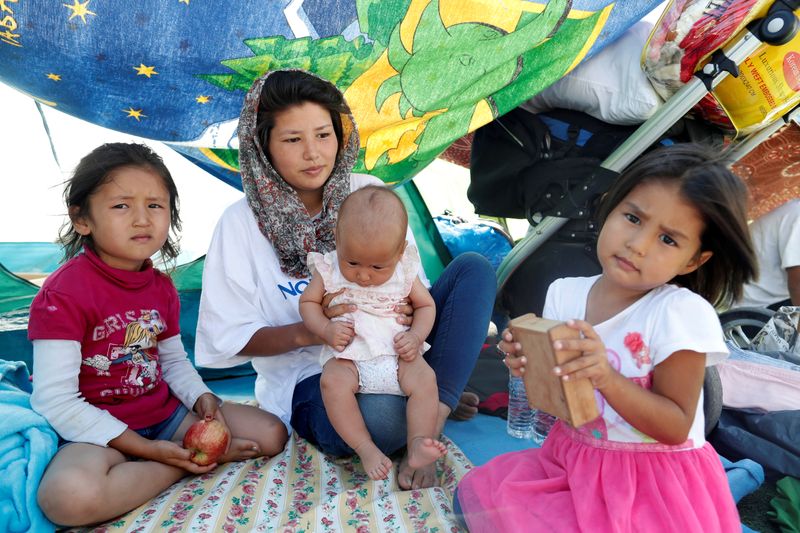 Una mujer afgana sentada junto a sus tres hijas frente a una tienda de campaña en el centro comunitario. REUTERS/Yara Nardi