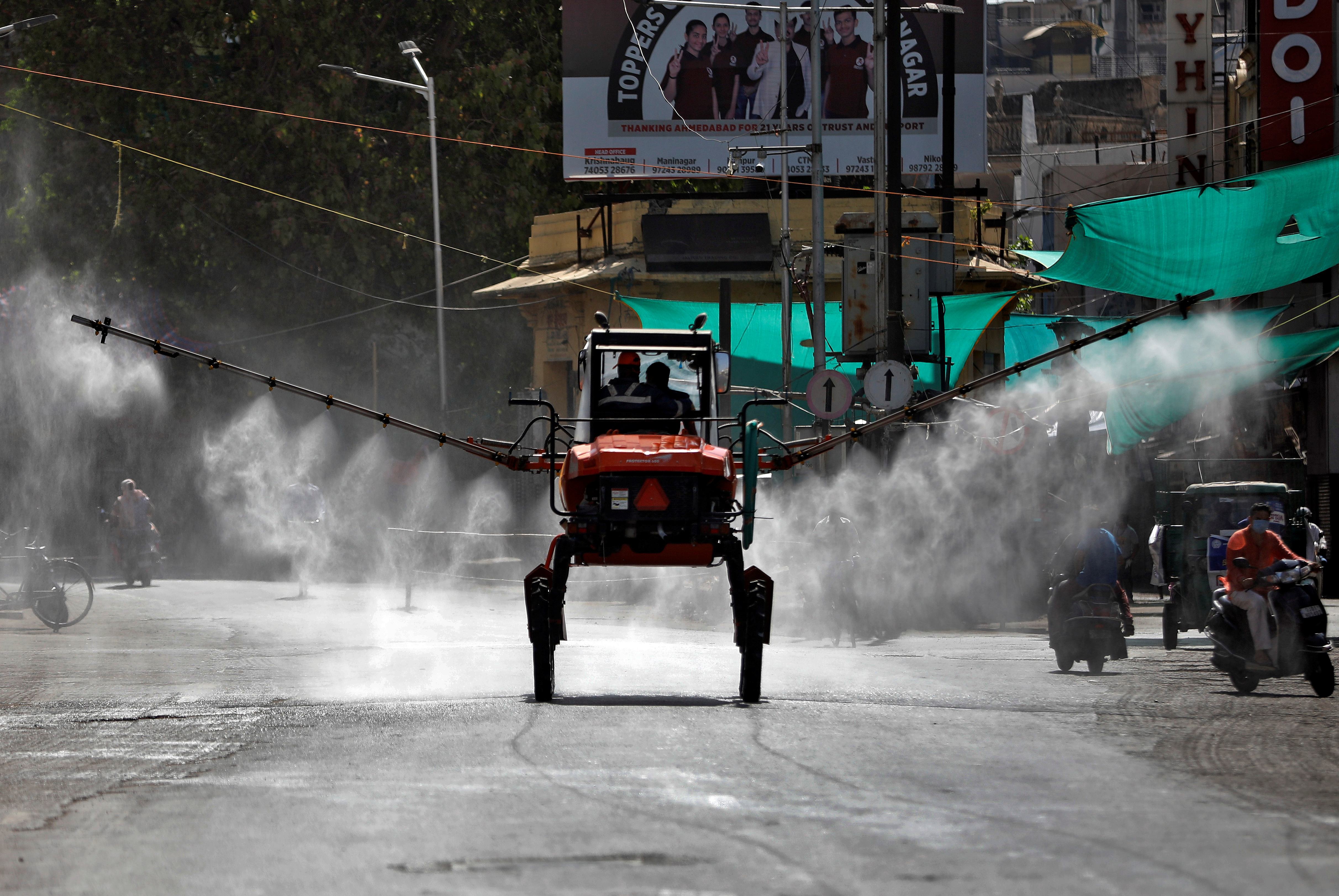 Miembros de los Servicios de Bomberos y Emergencias descontaminan una carretera utilizando un pulverizador de barra en Ahmedabad, India, el 24 de abril de 2020. REUTERS/Amit Dave