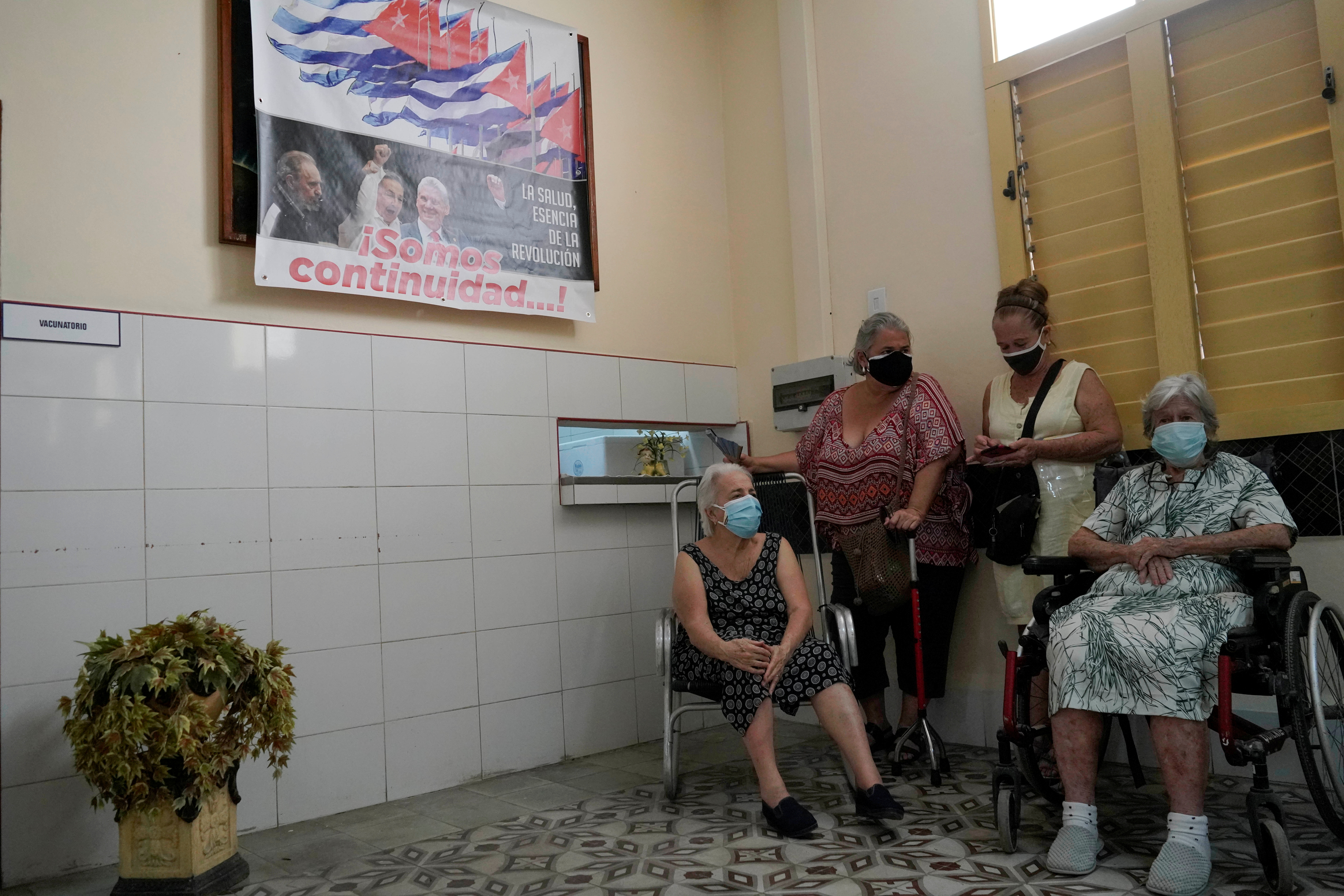 FOTO DE ARCHIVO: Personas esperan después de ser vacunadas contra el coronavirus bajo un cartel que muestra imágenes de Fidel Castro y Miguel Díaz-Canel y la frase "Somos continuidad", en un centro de vacunación en La Habana el 23 de junio de 2021. REUTERS/Alexandre Meneghini