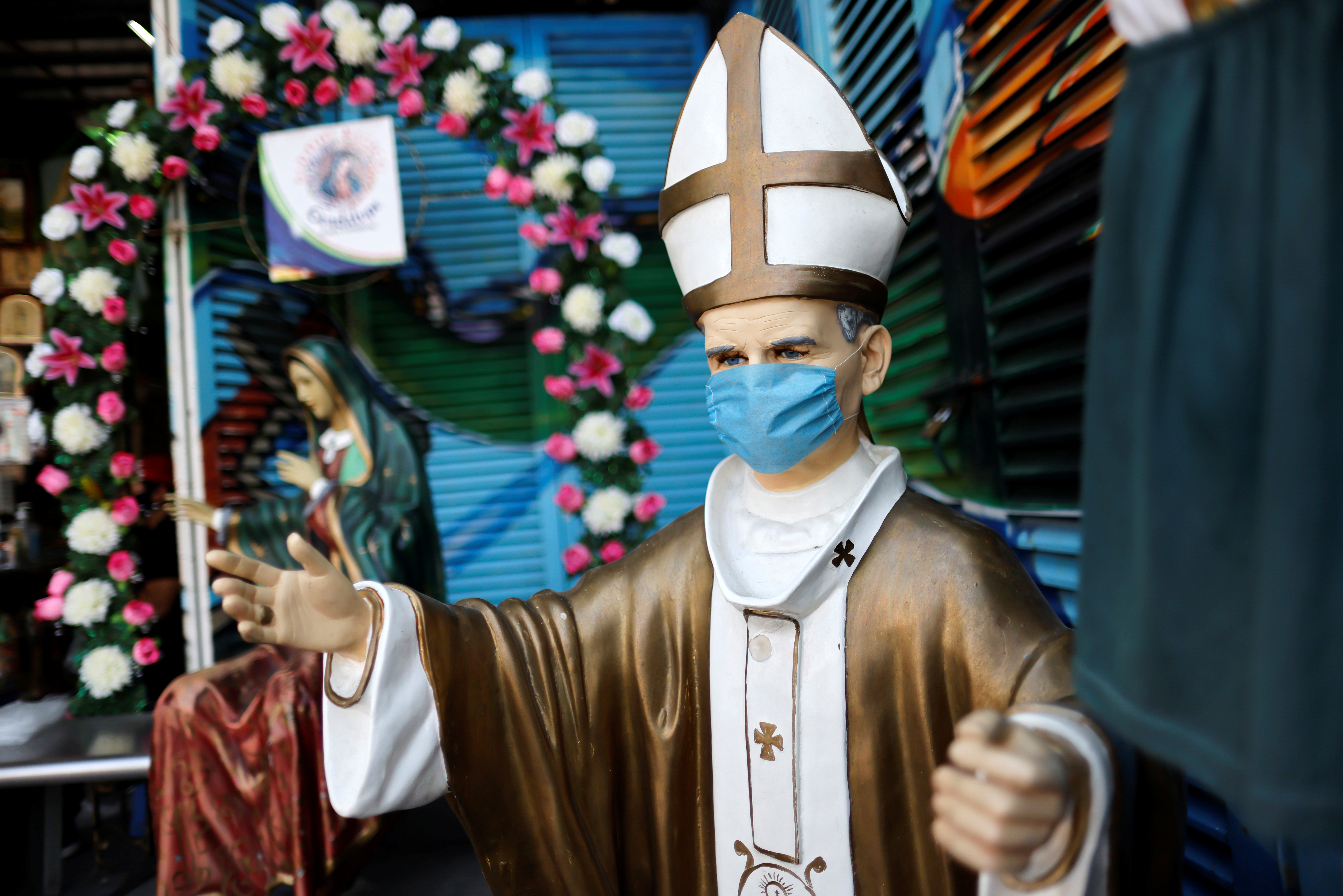 Una figura del difunto Papa Juan Pablo II con una máscara facial se ve cerca de la Basílica de Guadalupe que está temporalmente cerrada para evitar multitudes en el tradicional día de celebración de la Virgen de Guadalupe el 12 de diciembre, en la Ciudad de México, México, 10 de diciembre de 2020.