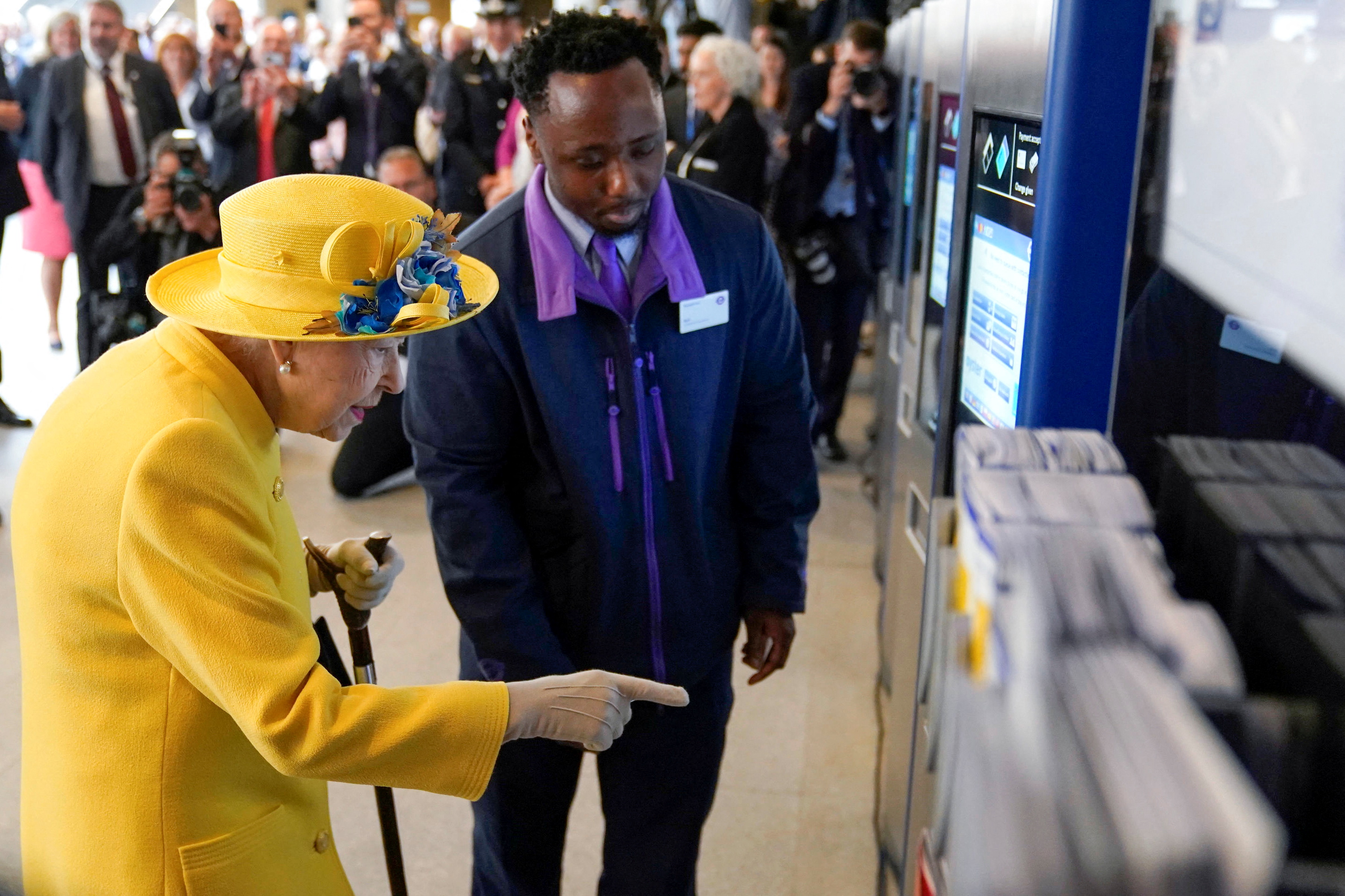 A la reina Isabel de Gran Bretaña se le muestra cómo comprar un boleto. (Andrew Matthews vía REUTERS)