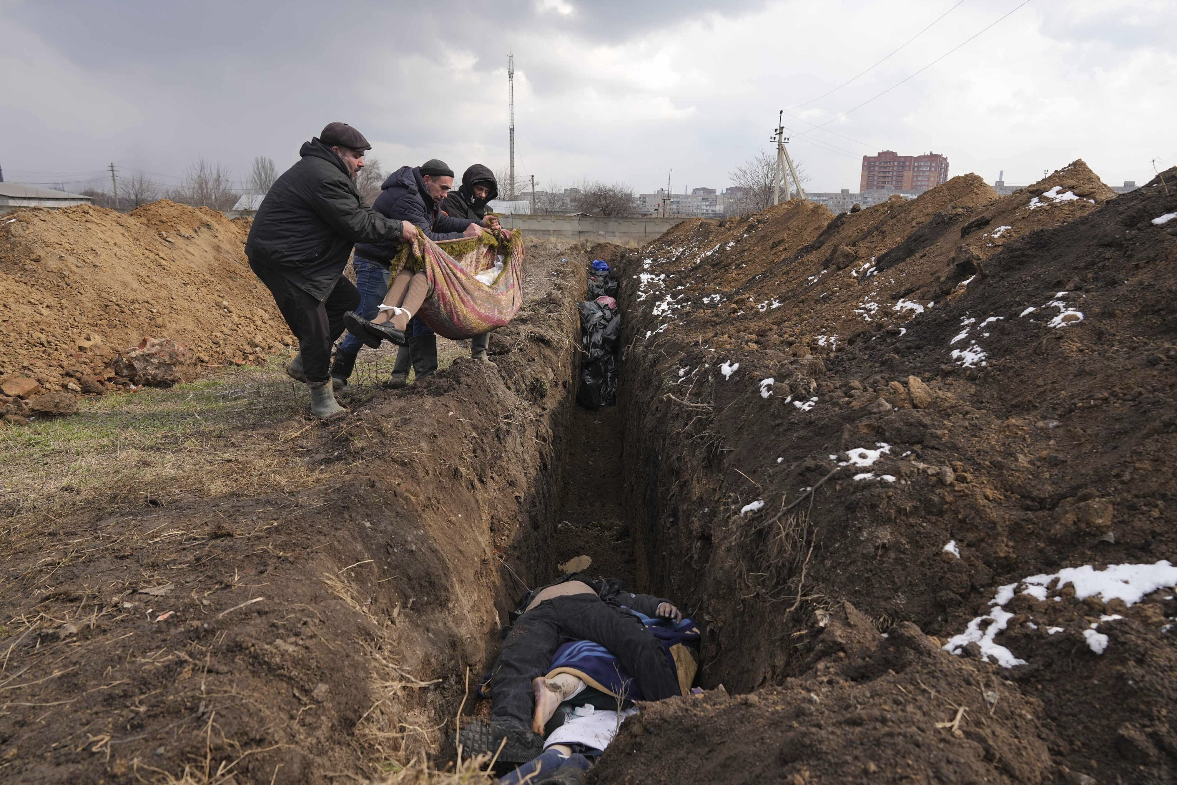Cadáveres siendo arrojados a una fosa común en las afueras de Mariúpol, Ucrania (AP Foto/Evgeniy Maloletka)
