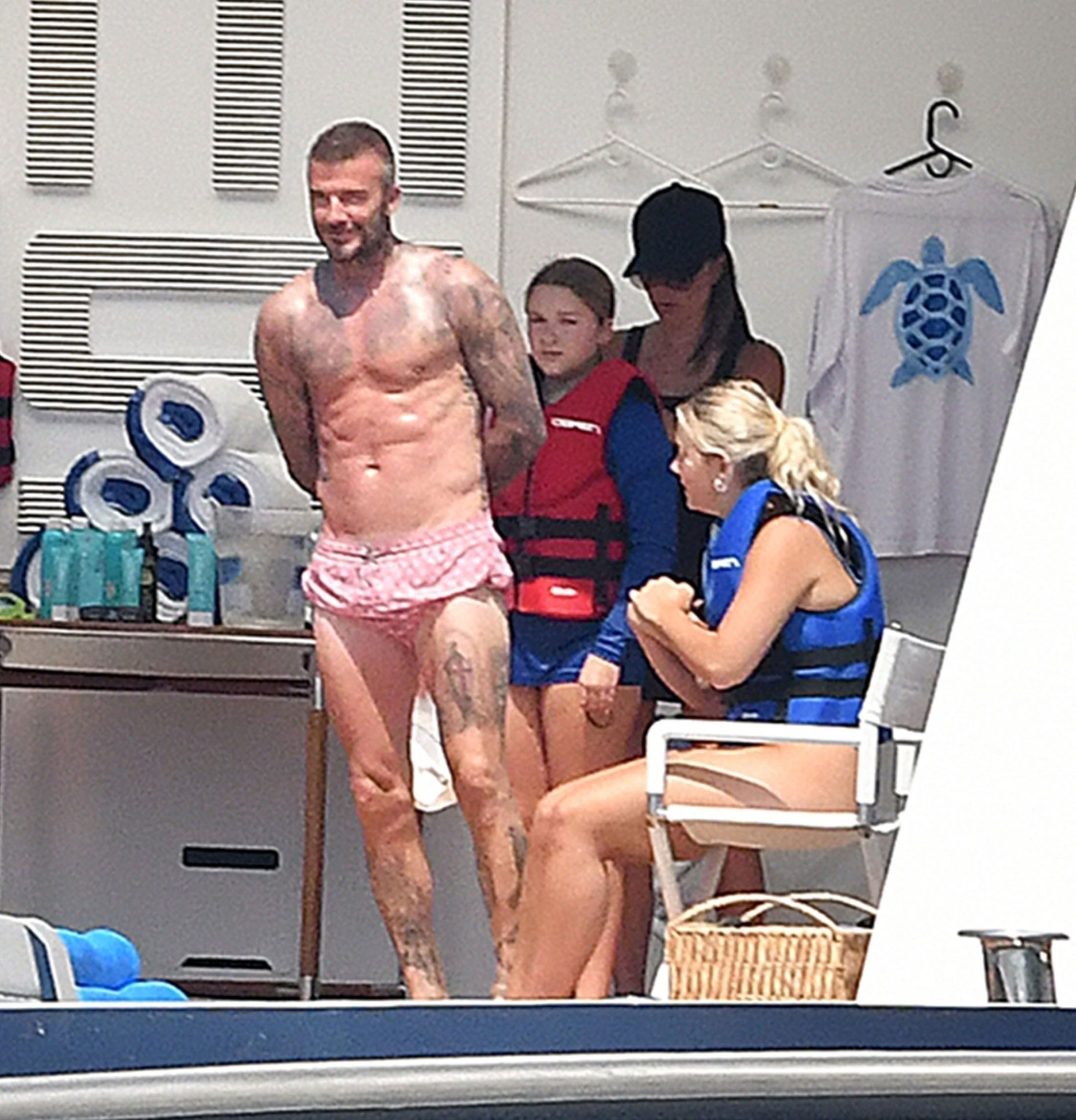 Former English soccer player David Beckham shows off his ripped abs as he relaxes with his wife Victoria Beckham, daughter Harper and son Cruz (who was with his girlfriend) on a yacht in Positano