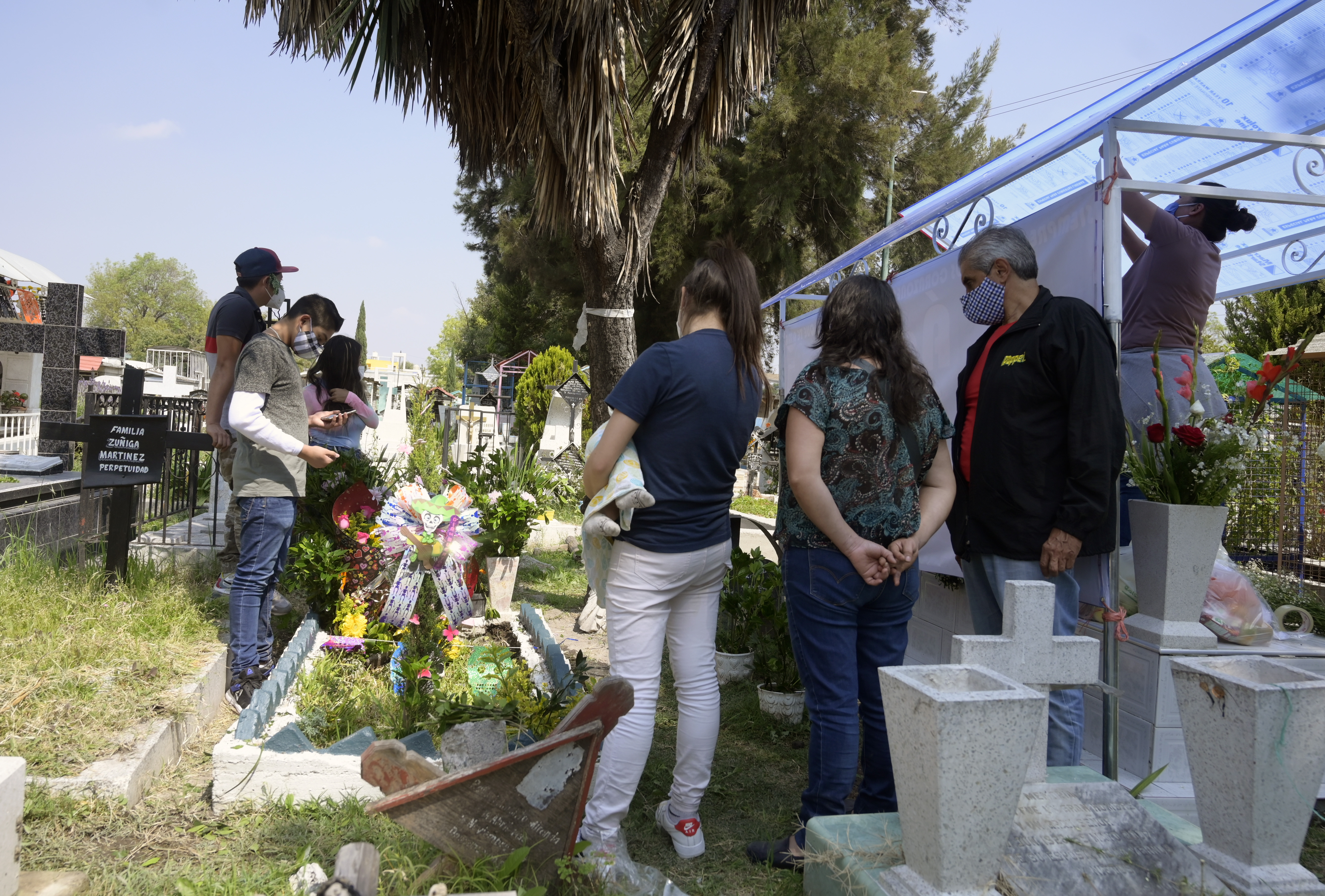 Una familia visita la tumba de un familiar antes del Día de Muertos en el Panteón San José, en la Ciudad de México, el 28 de octubre de 2020.