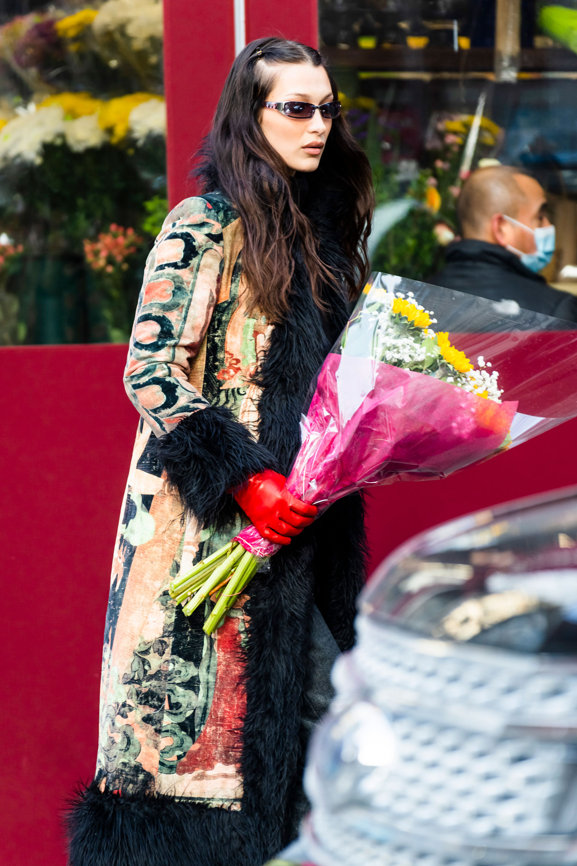 Bella Hadid fue fotografiada mientras compraba un ramo de flores para llevarle de regalo a su hermana Gigi, a quien fue a visitar a su casa en Nueva York. La modelo lució un pantalón y remera negra y un tapado multicolor con detalles de piel sintética 