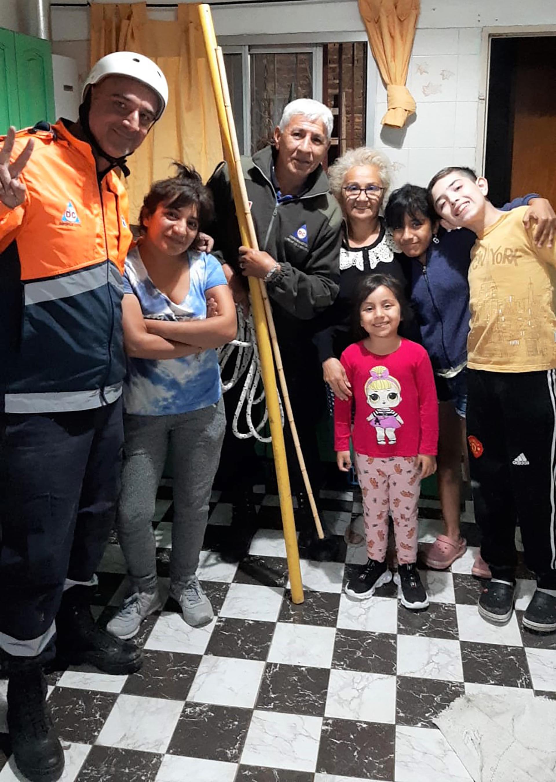 Martín Barbuto y Jorge Traba con la familia tras el rescate del perrito (Defensa Civil Lomas)