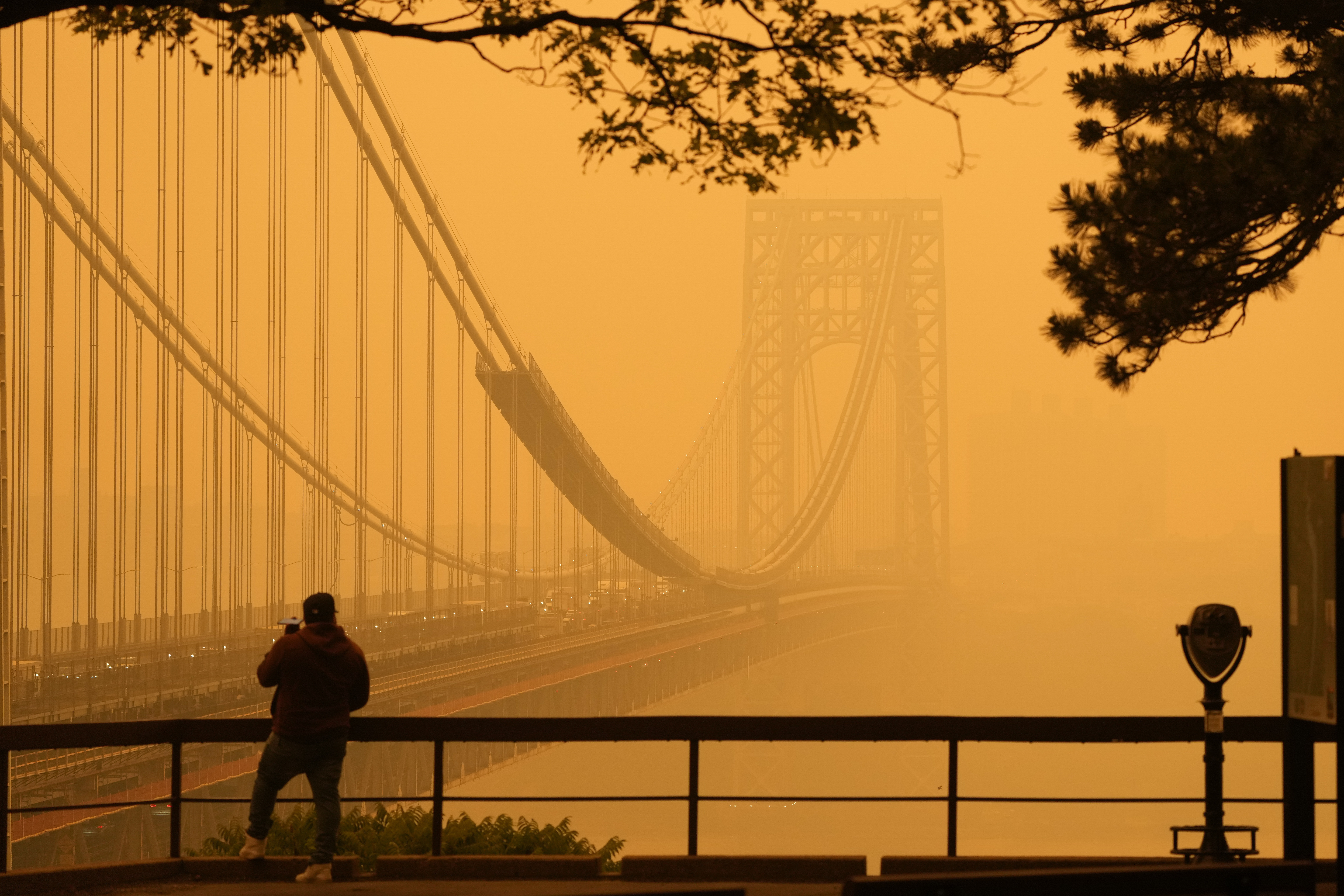Un hombre habla por teléfono mientras observa la bruma en el puente George Washington, visto desde Fort Lee, Nueva Jersey (AP Foto/Seth Wenig)