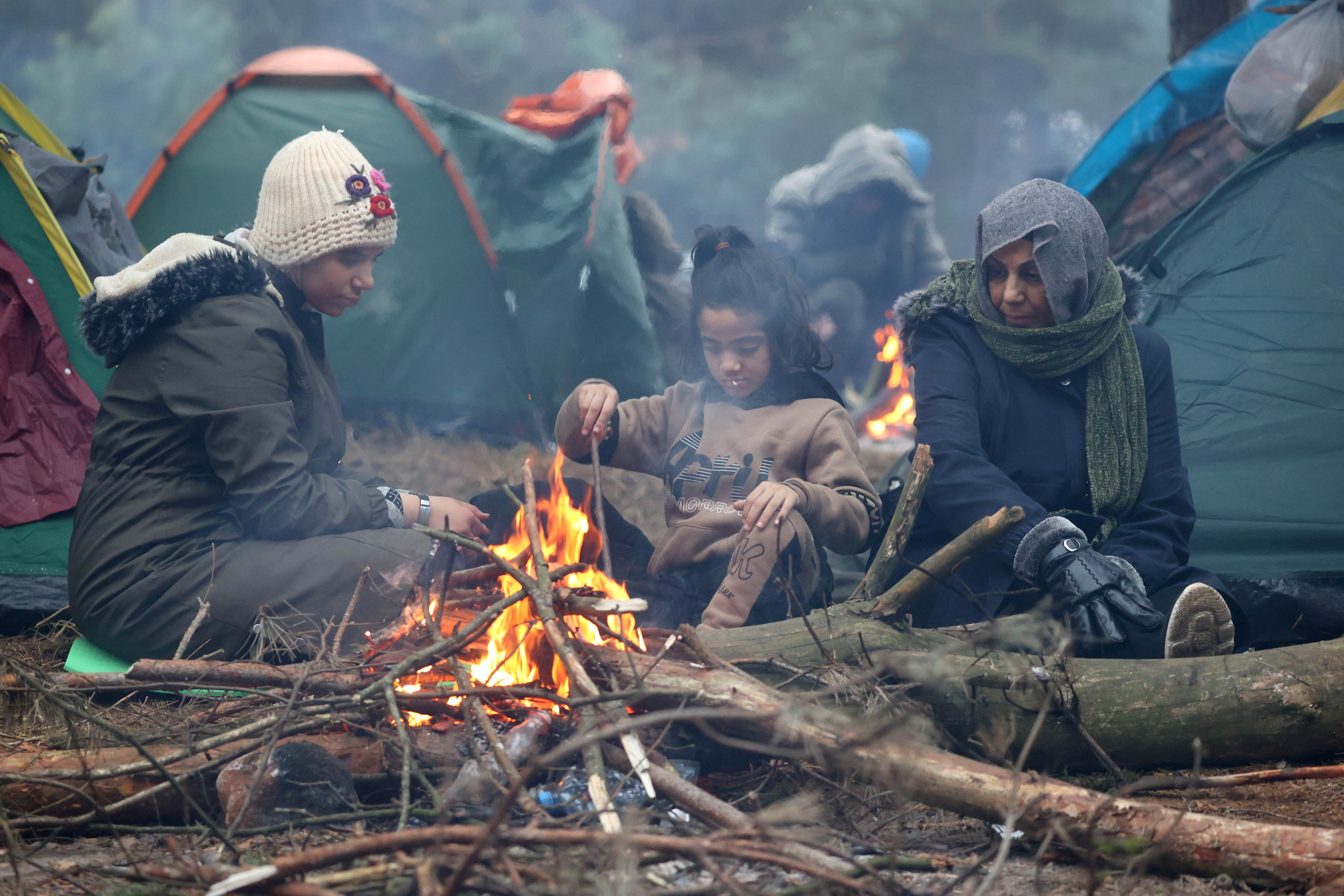 Migrantes se reúnen cerca de una fogata para mantener la temperatuira a medida que el frío comienza a golpear Europa en la frontera bielorrusa-polaca en la región de Grodno, Bielorrusia (Reuters)