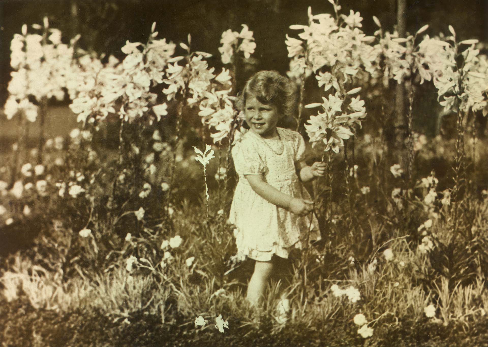 Sus padres la llamaron Elizabeth Alexandra Mary en honor a su madre, a su bisabuela paterna y a su abuela paterna, respectivamente. Esta foto fue tomada por su padre mientras la pequeña recogía flores en el jardín del palacio 