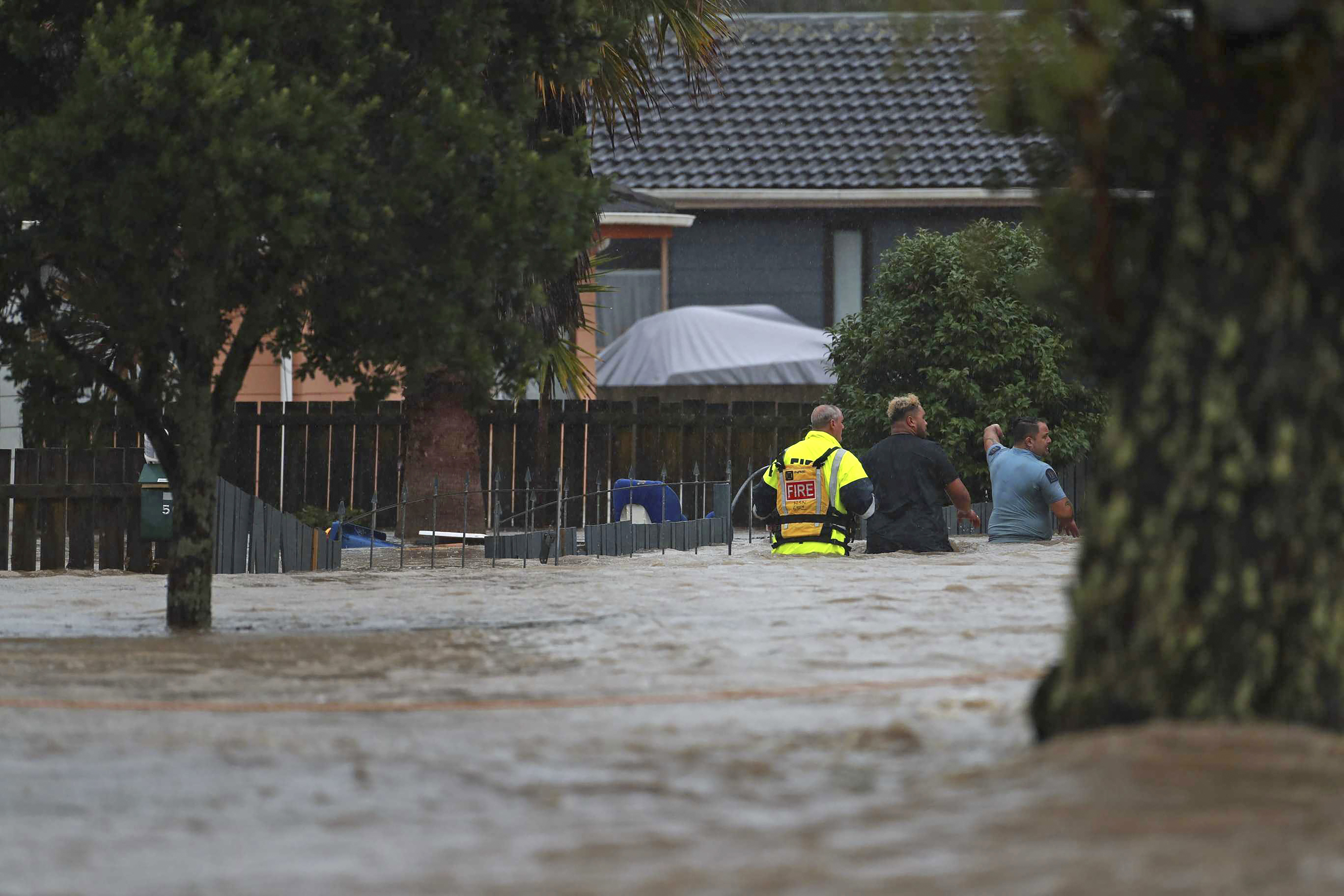 Personal de emergencia y un hombre atraviesan las aguas de una inundación en Auckland, Nueva Zelanda, el viernes 27 de enero de 2023. (Hayden Woodward/New Zealand Herald vía AP)