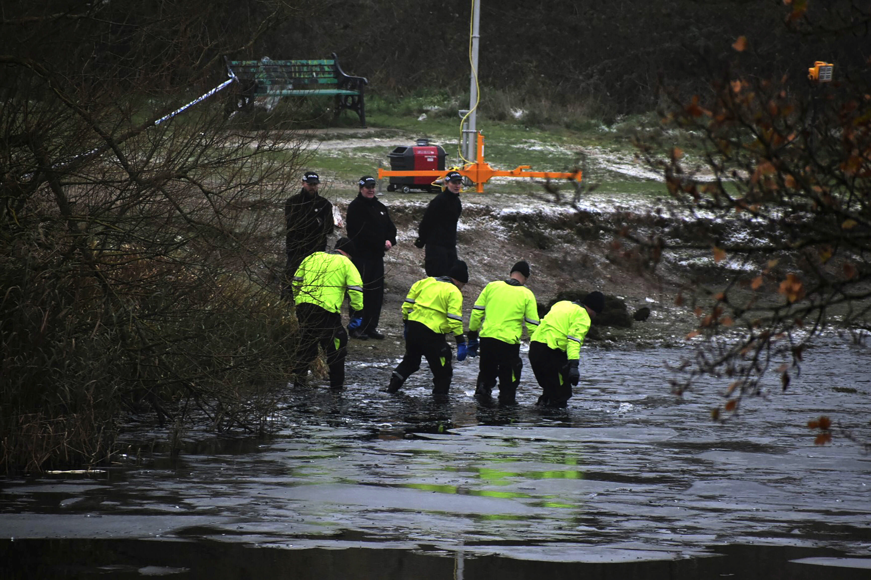 Equipos de búsqueda de la policía buscan en un lago congelado luego de que cuatro niños cayeron a las aguas gélidas y tres de ellos murieron; el cuarto estaba muy grava, en Babbs Mill Park en Kingshurst, Solihull, Inglaterra, el lunes 12 de diciembre de 2022. (Matthew Cooper/PA vía AP)