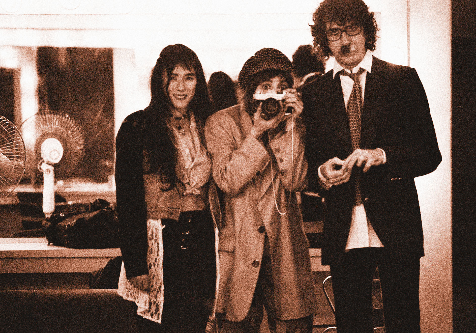 Hilda con su cámara fotográficoa junto a María Gabriela Epumer (1963-2003) y Charly García
