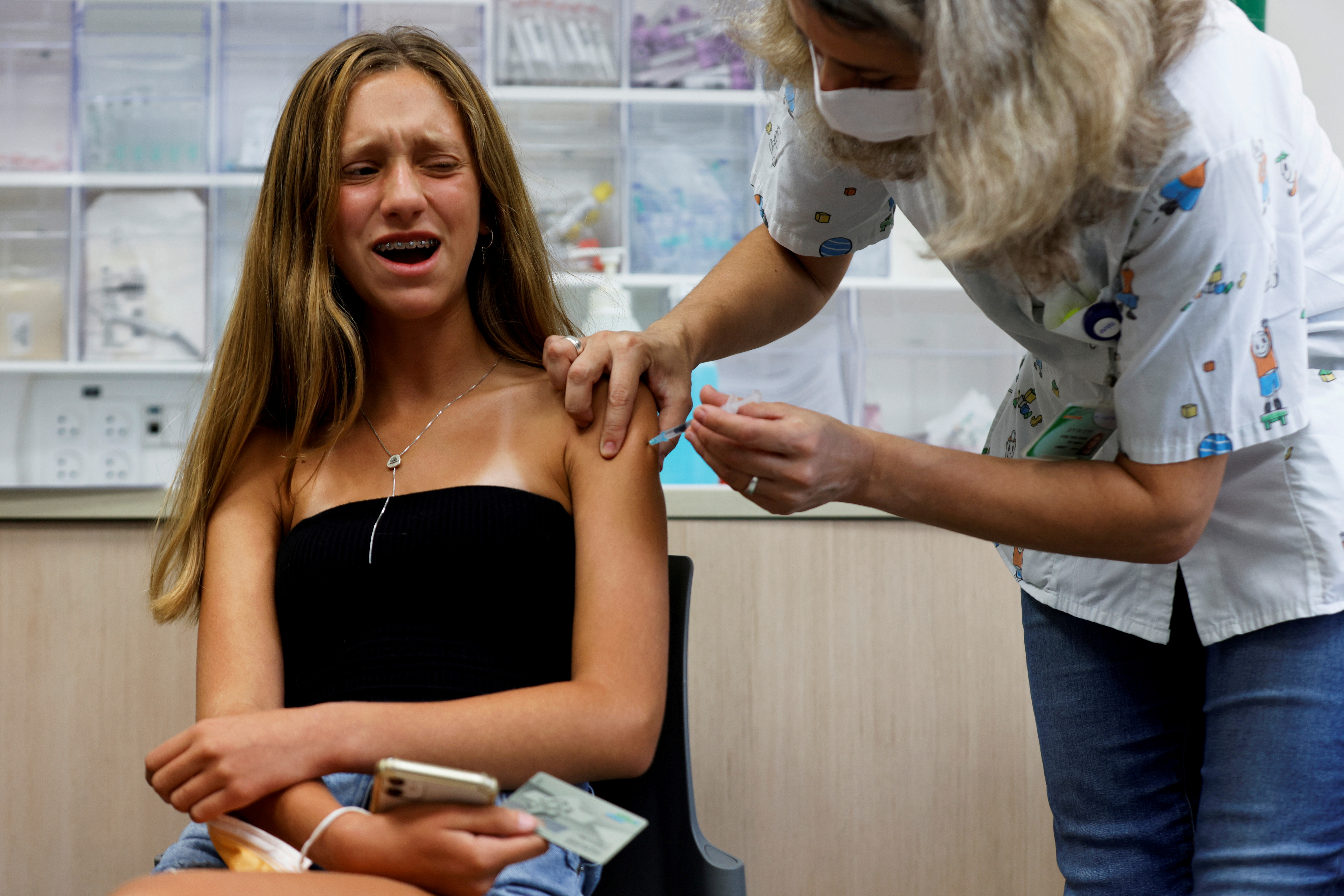FILE PHOTO: A teenager reacts while receiving a dose of a vaccine against the coronavirus disease (COVID-19) as Israel urged more 12- to 15-year-olds to be vaccinated, citing new outbreaks attributed to the more infectious Delta variant, at a Clalit healthcare maintenance organisation in Tel Aviv, Israel June 21, 2021. REUTERS/Amir Cohen/File Photo