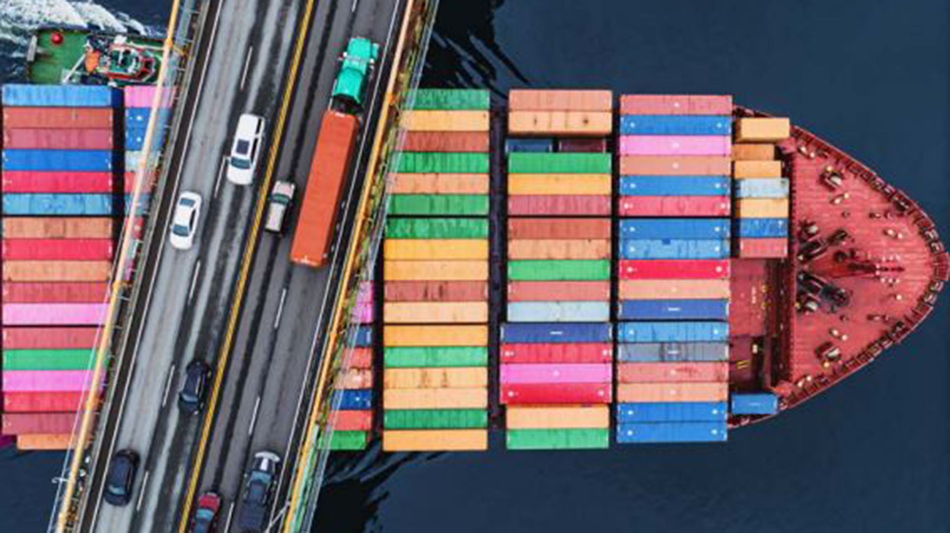 La vista aérea de un buque portacontenedor atravesando un puente sugiere el peso decisivo del tráfico marítimo en el comercio mundial