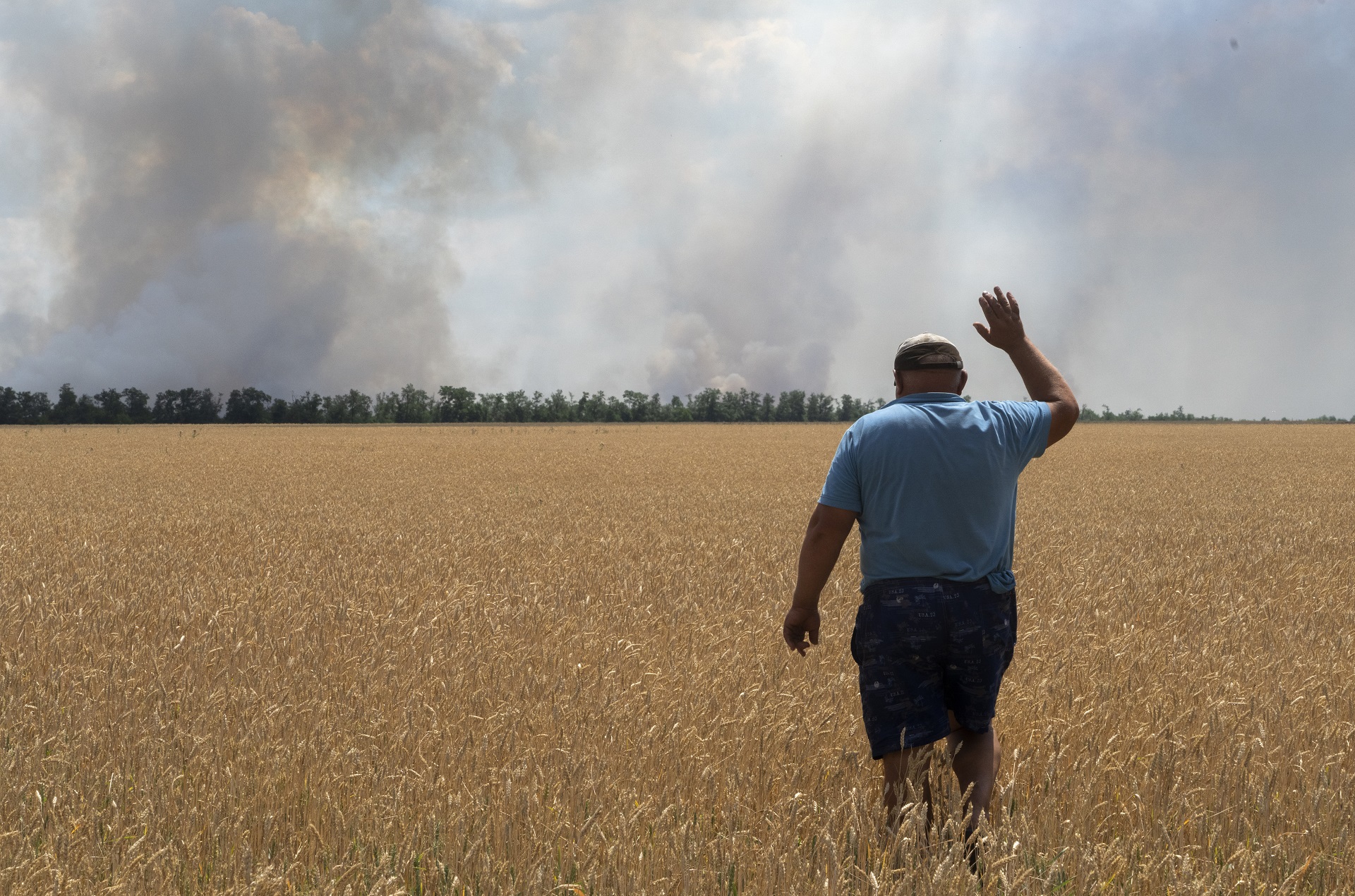 Un campesino reacciona mientras mira a su campo incendiado por los combates en el frente