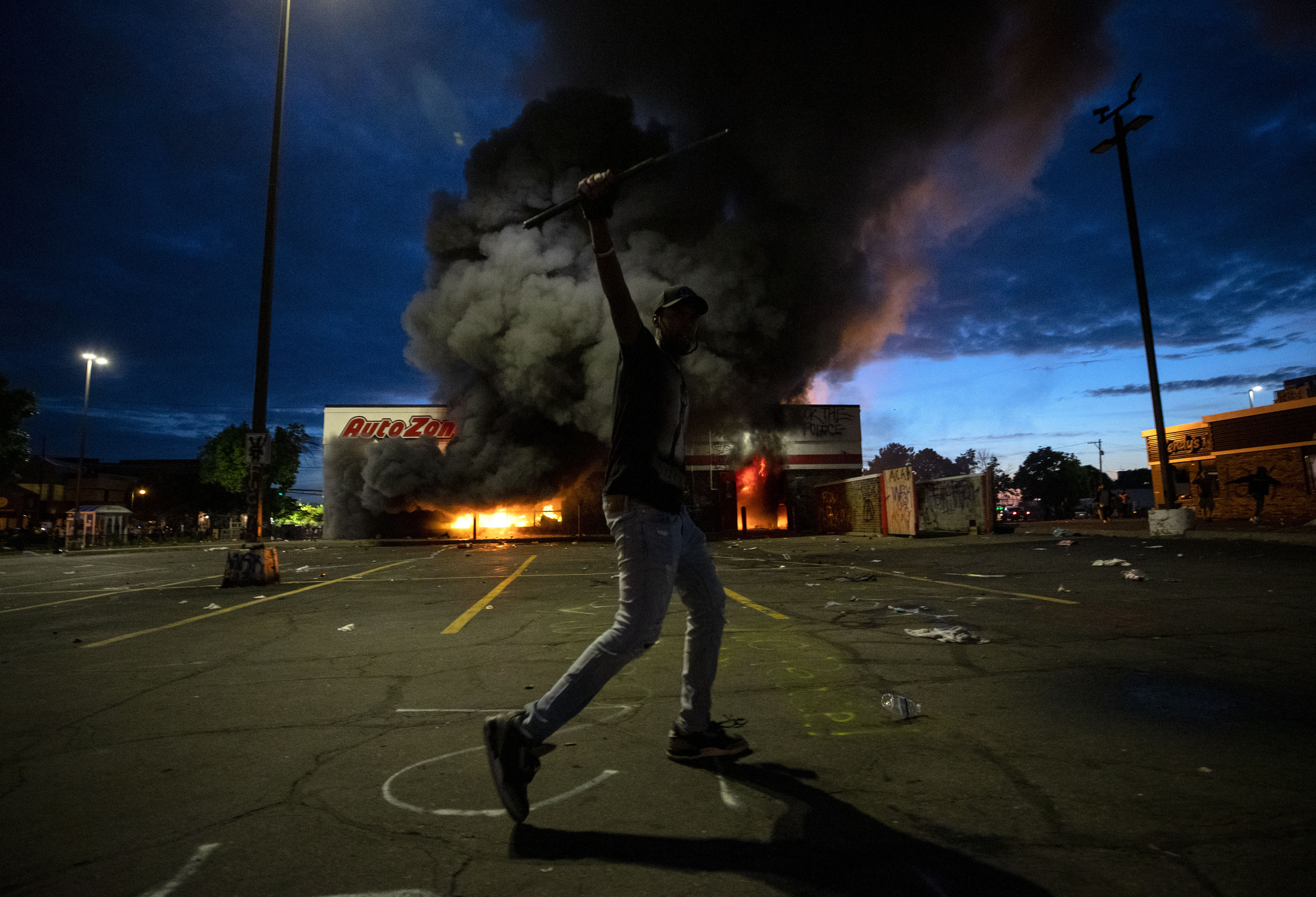 Un hombre frente a la tienda de autopartes AutoZone incendiada (Carlos Gonzalez/Star Tribune via AP)