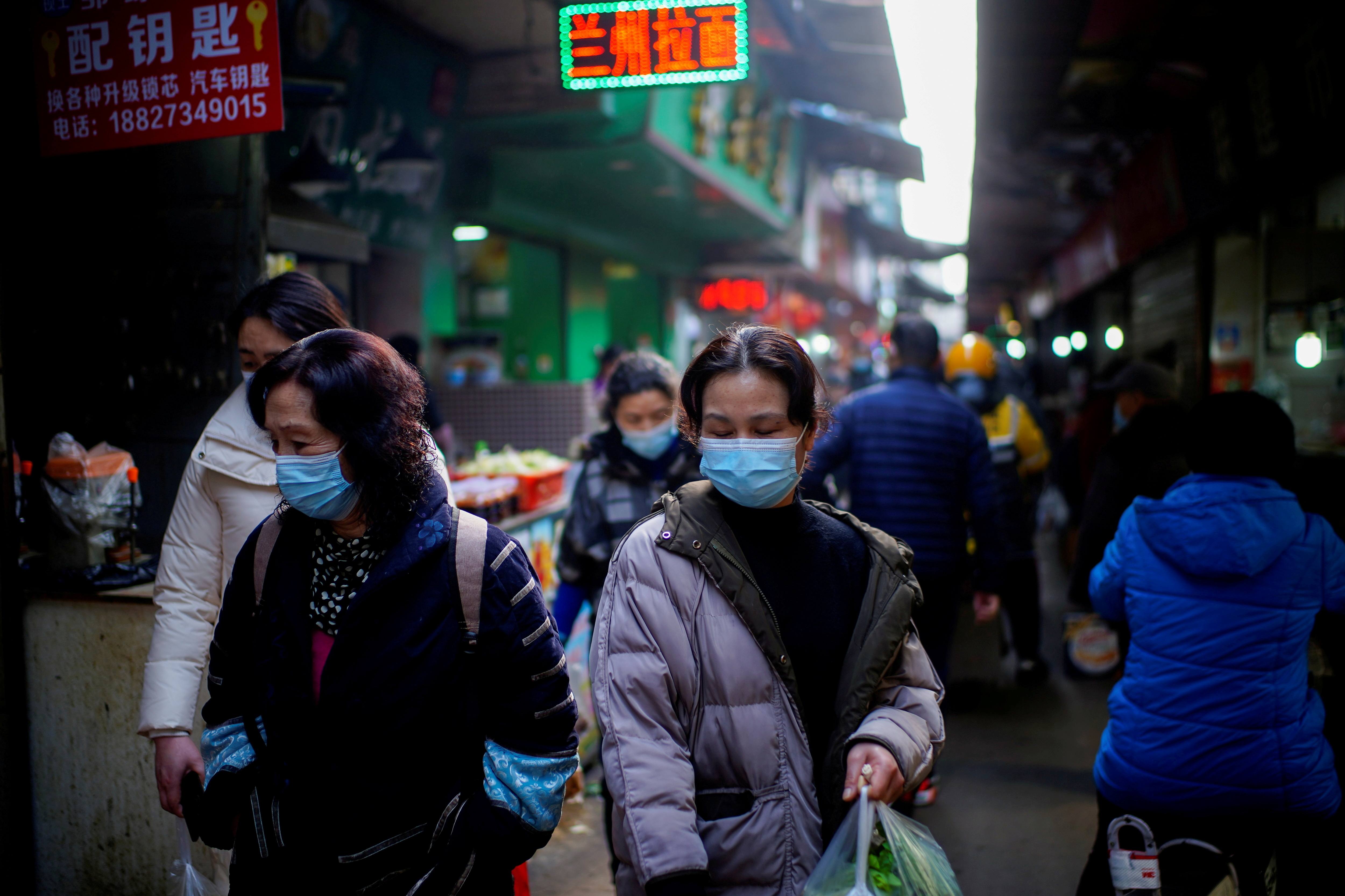 FOTO DE ARCHIVO: Personas con mascarillas caminan en un mercado callejero, tras un brote de la enfermedad del coronavirus (COVID-19) en Wuhan, provincia de Hubei, China 8 de febrero de 2021. REUTERS/Aly Song
