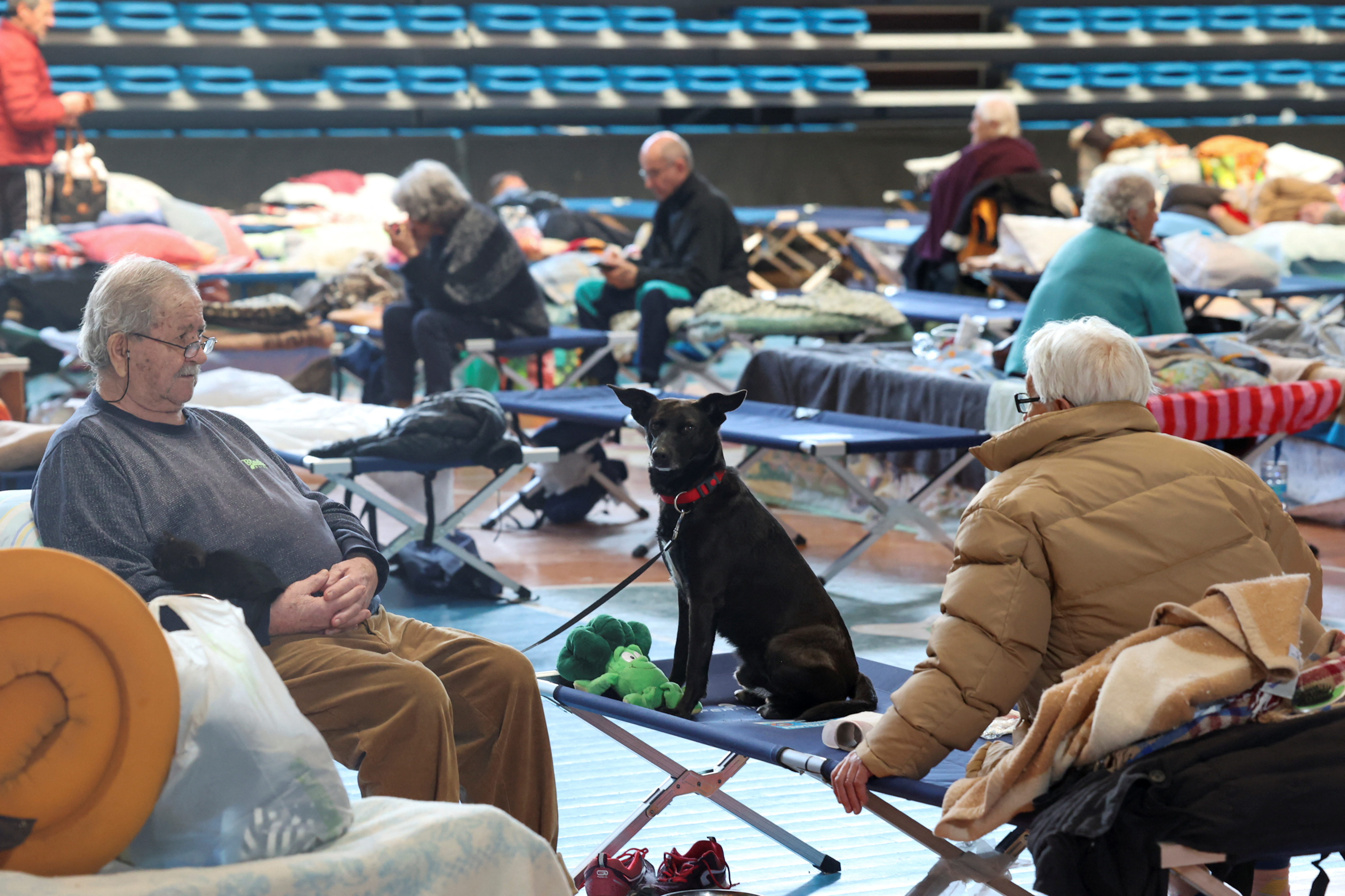 Un grupo de personas sentadas en el refugio armado en el centro deportivo PalaCattani en Faenza, Italia, el 18 de mayo de 2023 (REUTERS/Claudia Greco)