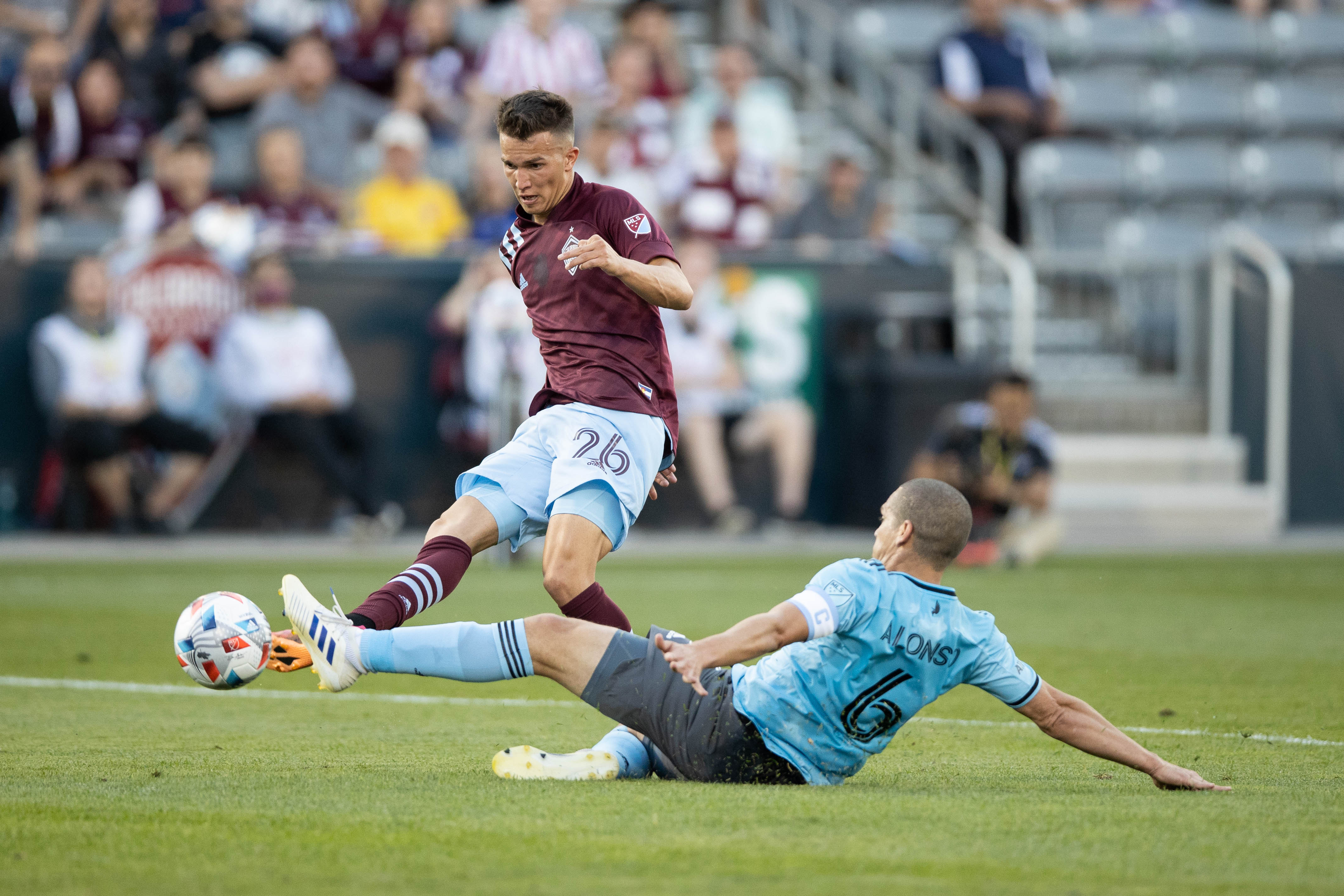 Jul 7, 2021; Commerce City, Colorado, USA; Colorado Rapids midfielder Cole Bassett (26) takes a shot as Minnesota United FC midfielder Osvaldo Alonso (6) defends in the first half at Dick's Sporting Goods Park. Mandatory Credit: Isaiah J. Downing-USA TODAY Sports