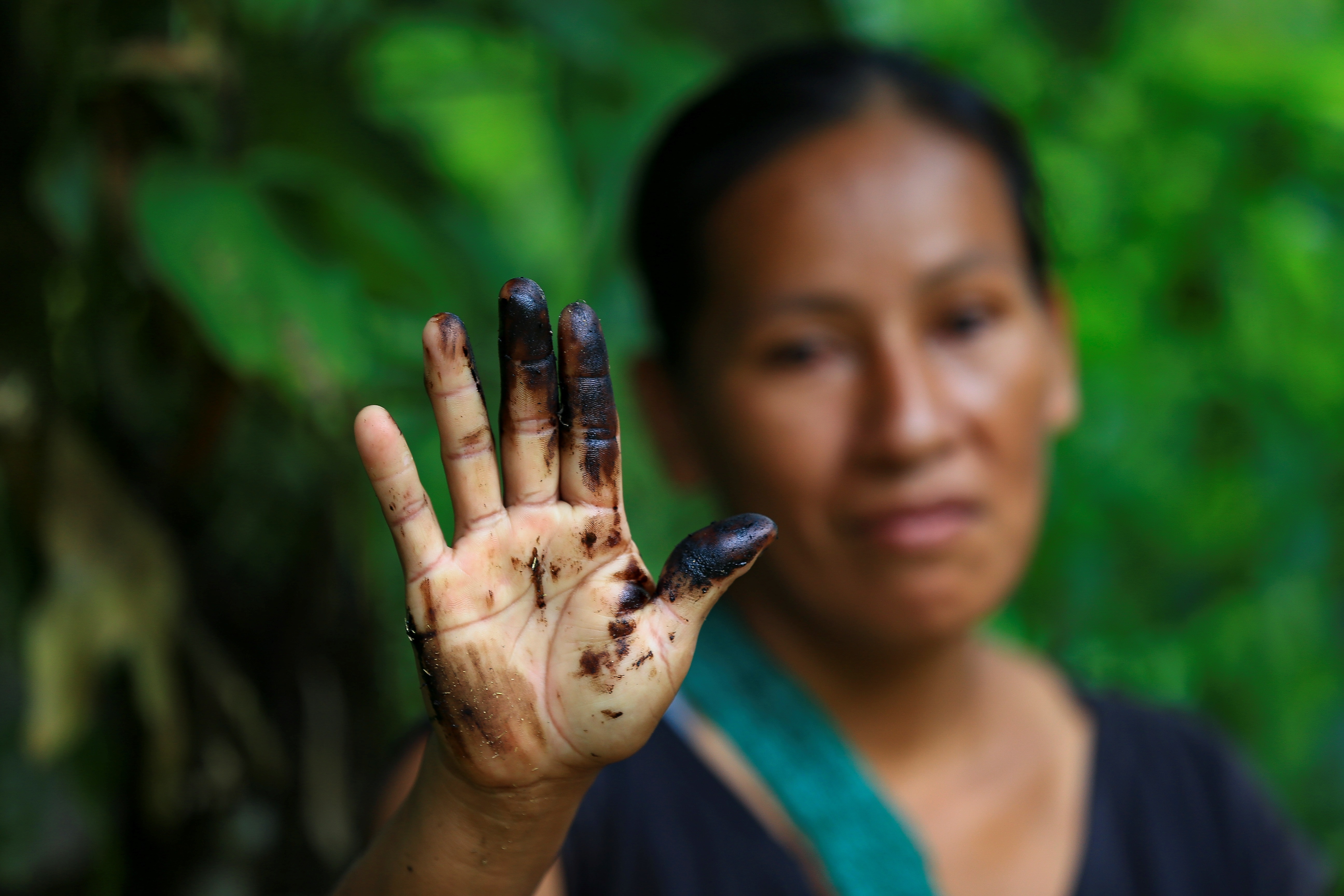 Una indígena de la comunidad de Amarumesa muestra en su mano residuos de petróleo en la Amazonía ecuatoriana (EFE/José Jácome)

