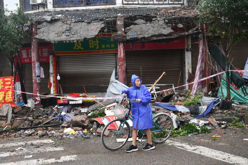 Una persona empuja una bicicleta frente a los edificios dañados, tras un terremoto en China