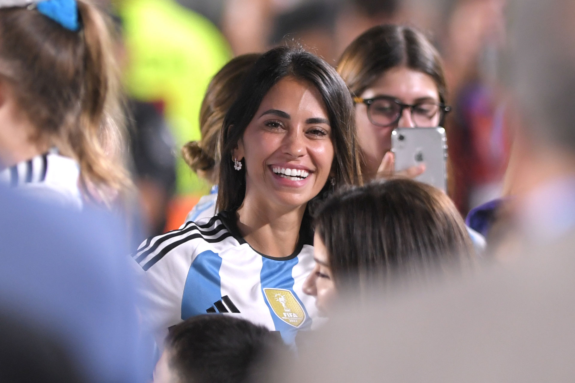 Antonela Roccuzzo smiles.  The families of the soccer players entered the field of play before the match