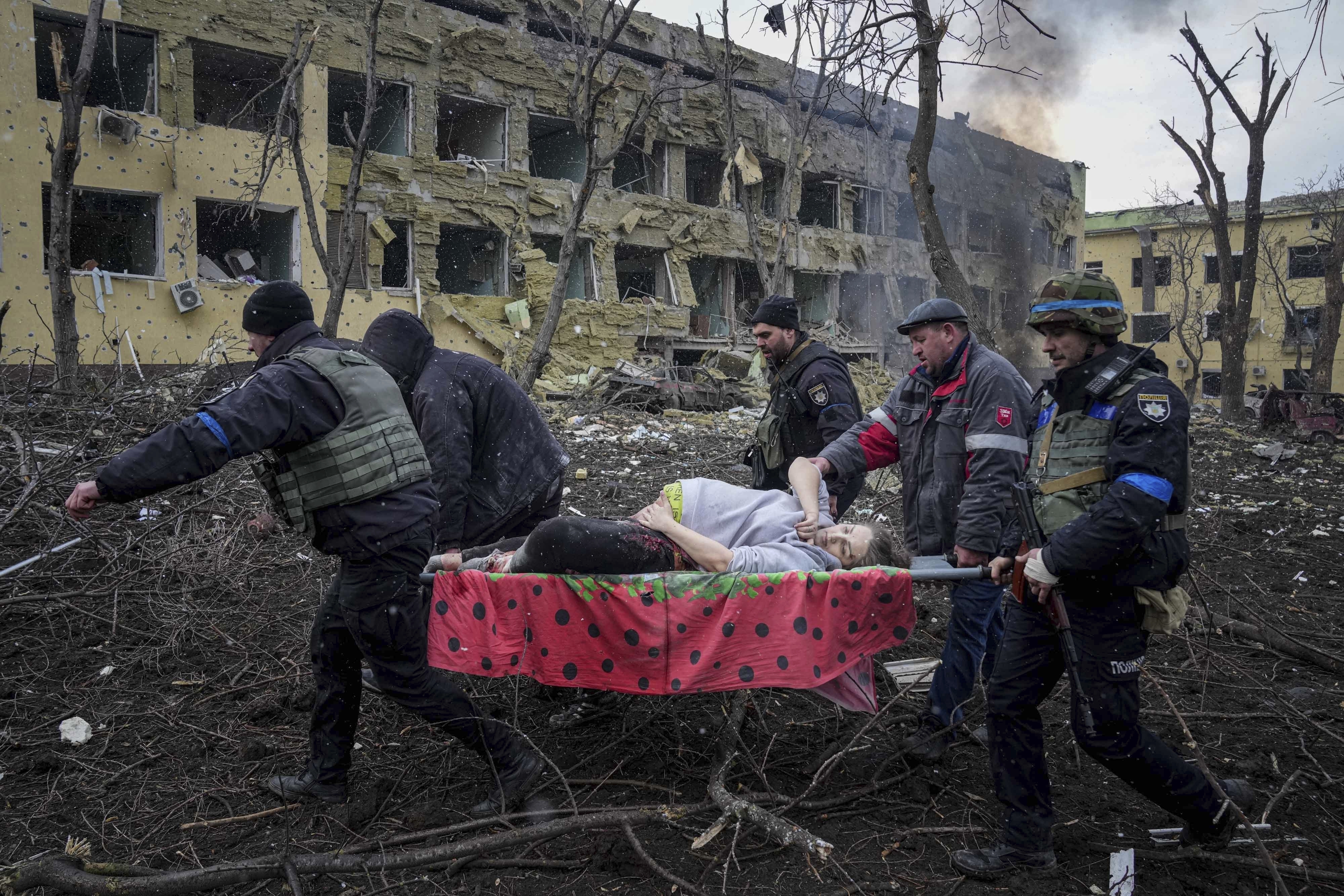 El bombardeo en Mariupol, que Rusia niega y acusa de ser noticias falsas. Rescatistas y voluntarios ucranianos cargan a una mujer embarazada herida desde un hospital de maternidad dañado por un ataque aéreo en marzo de 2022 (AP Foto/Evgeniy Maloletka)