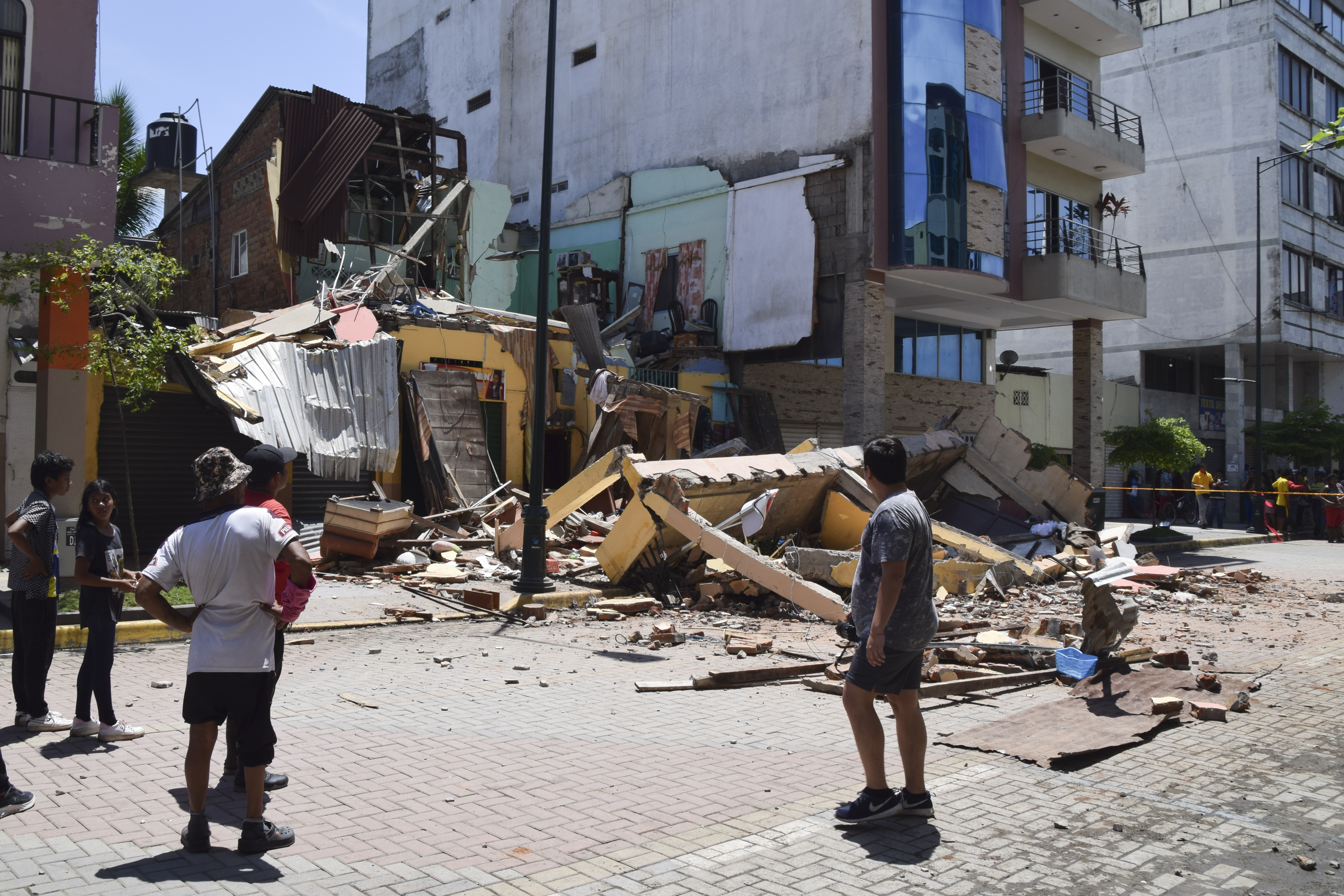 Los residentes miran un edificio que se derrumbó después de que un terremoto sacudiera Machala, Ecuador, el sábado 18 de marzo de 2023. El Servicio Geológico de EEUU informó que el sismo de 6,7 tuvo su epicentro frente a la costa del Pacífico, a unas 50 millas (80 kilómetros) al sur de Guayaquil. (Foto AP/Jhonny Crespo)