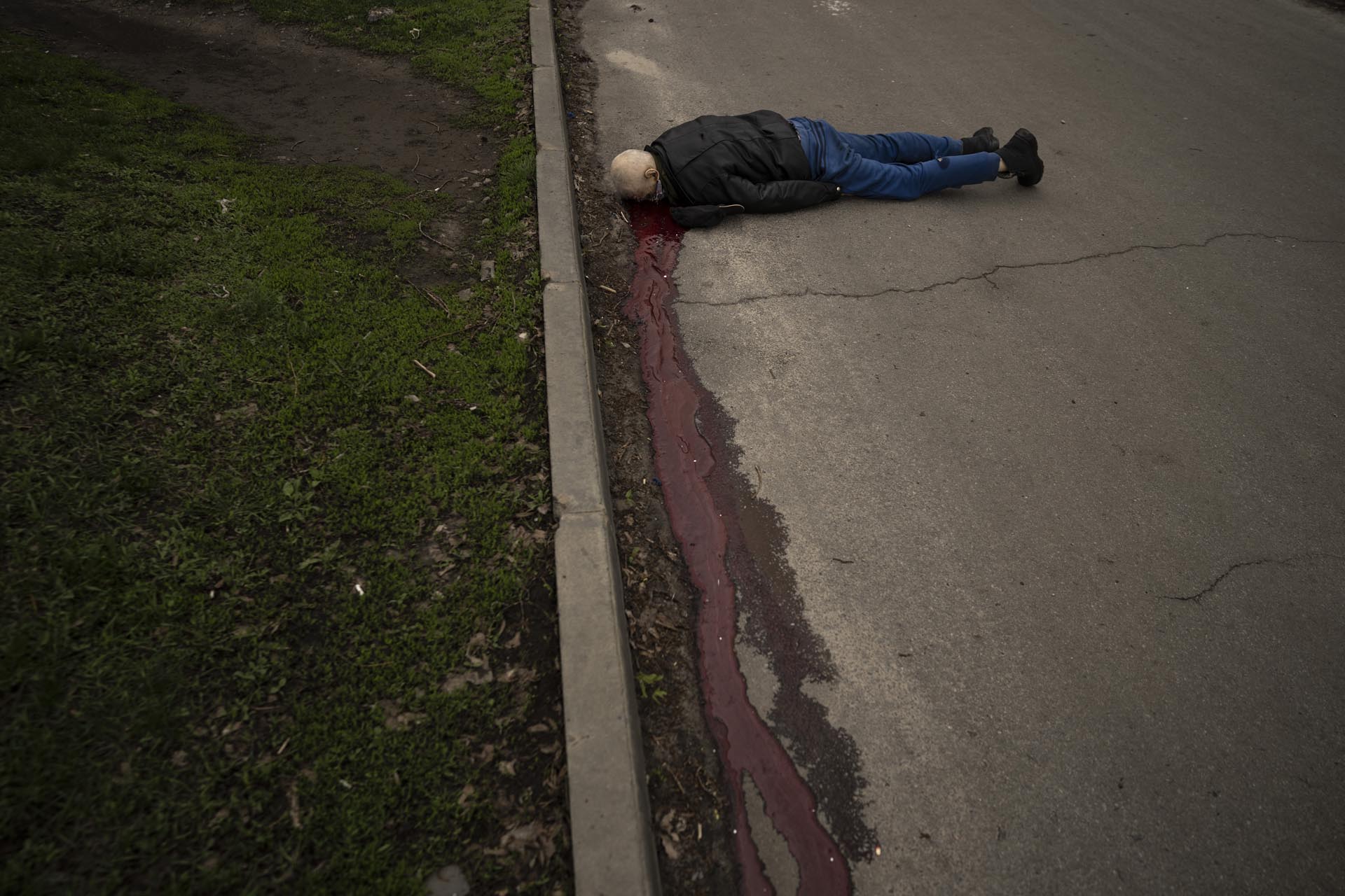 El cuerpo de un hombre muerto durante un bombardeo ruso se ve en una calle de un vecindario residencial en Járkiv, Ucrania, el martes 19 de abril de 2022.