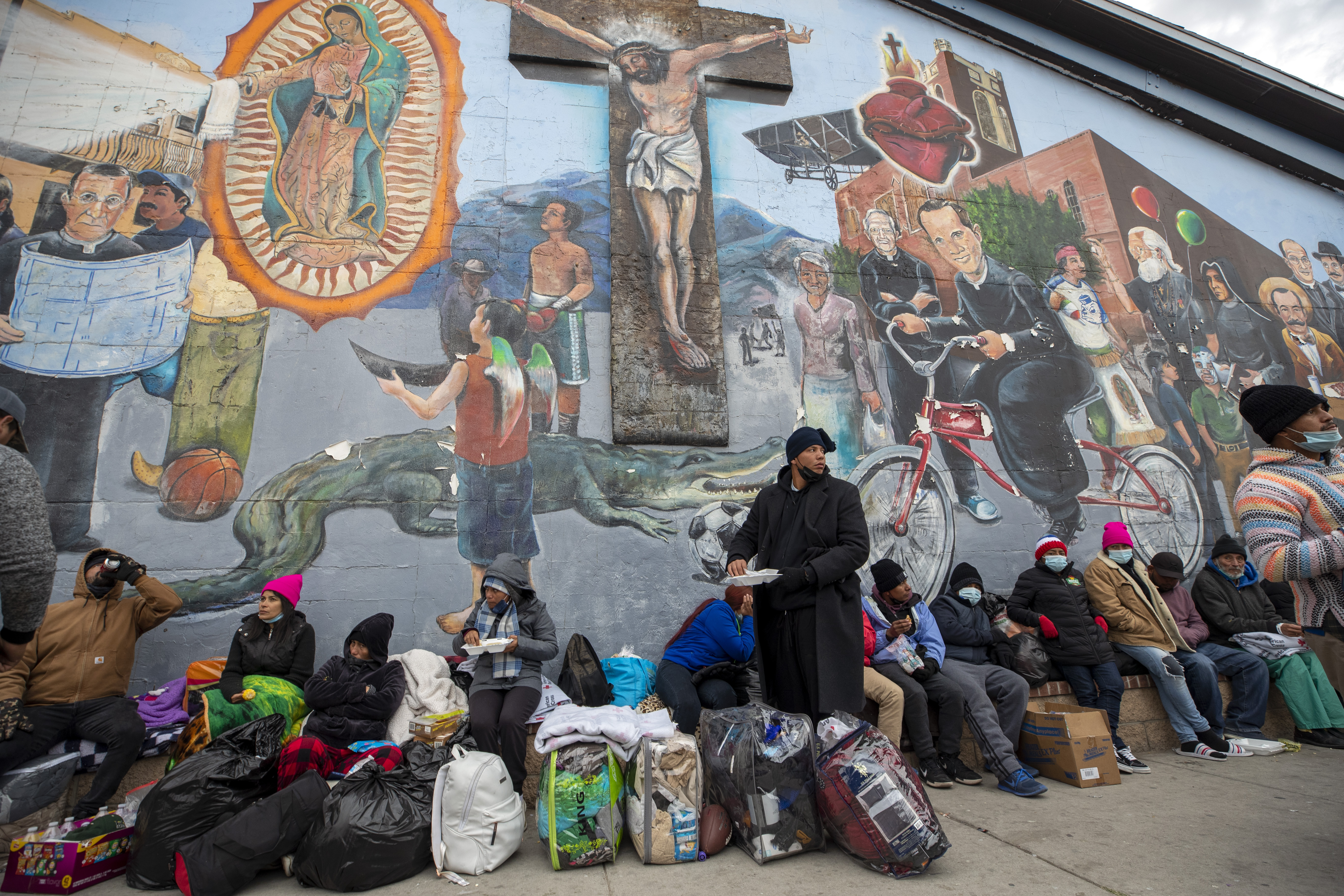 Migrantes comen y esperan ayuda, acampados en una calle del centro de El Paso, Texas (AP Foto/Andres Leighton)