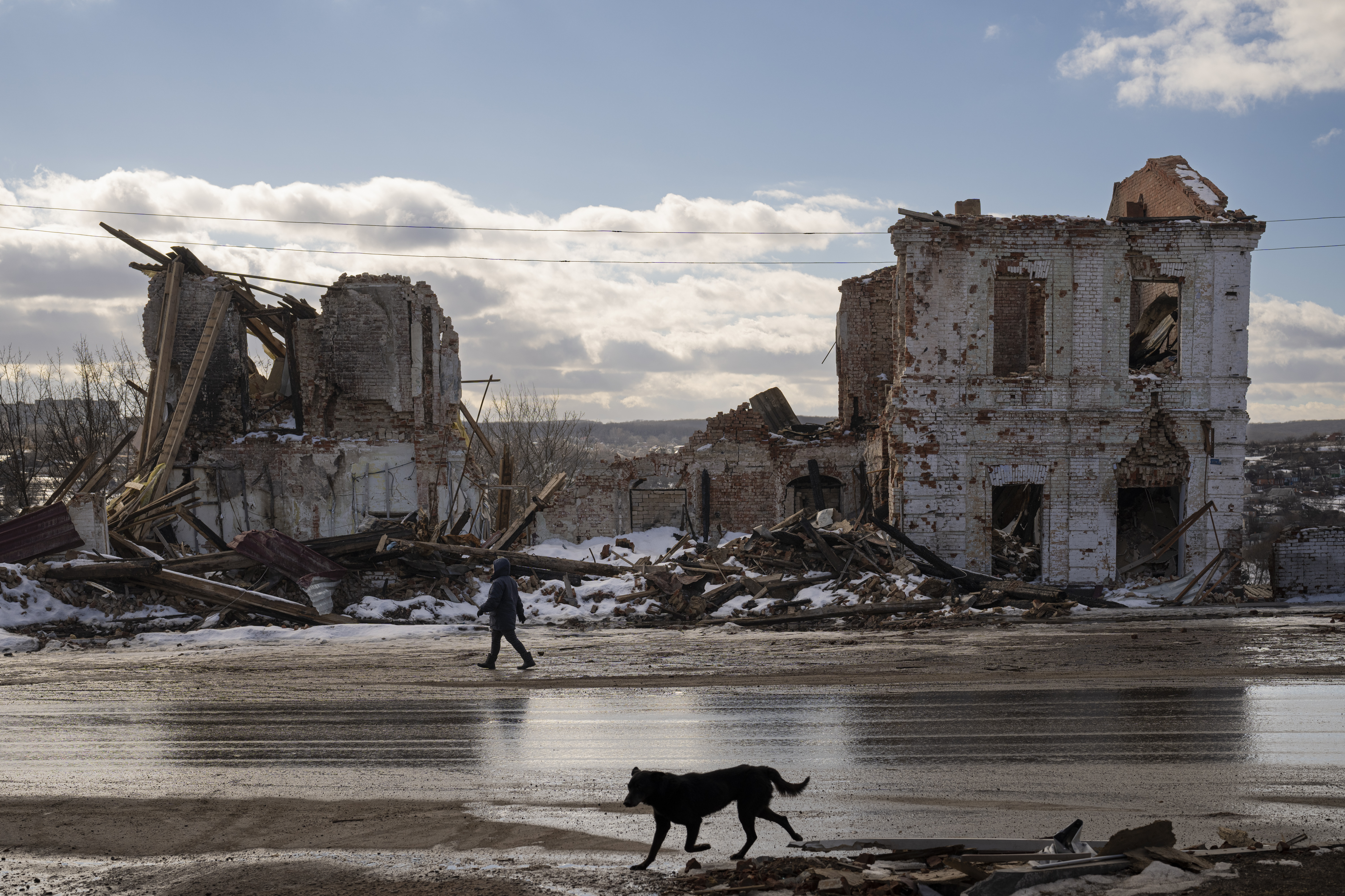 Archivo - Una mujer camina frente a casas destruidas por un ataque ruso en Kupiansk, Ucrania, el lunes 20 de febrero de 2023. (AP Foto/Vadim Ghirda, Archivo)